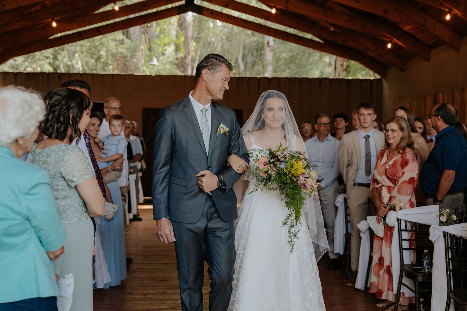 Bride walks down the aisle with escort at an outdoor wedding ceremony in Mpumalanga