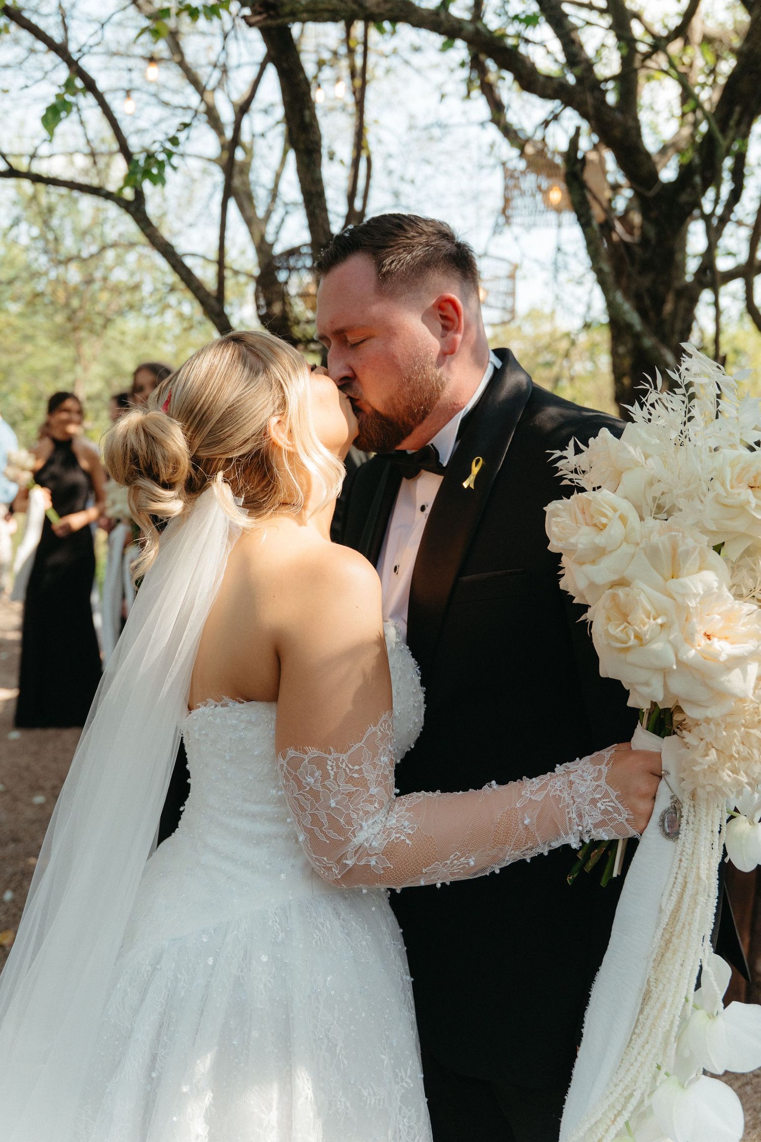 A romantic wedding moment captured as a couple embraces during their outdoor ceremony surrounded by guests.