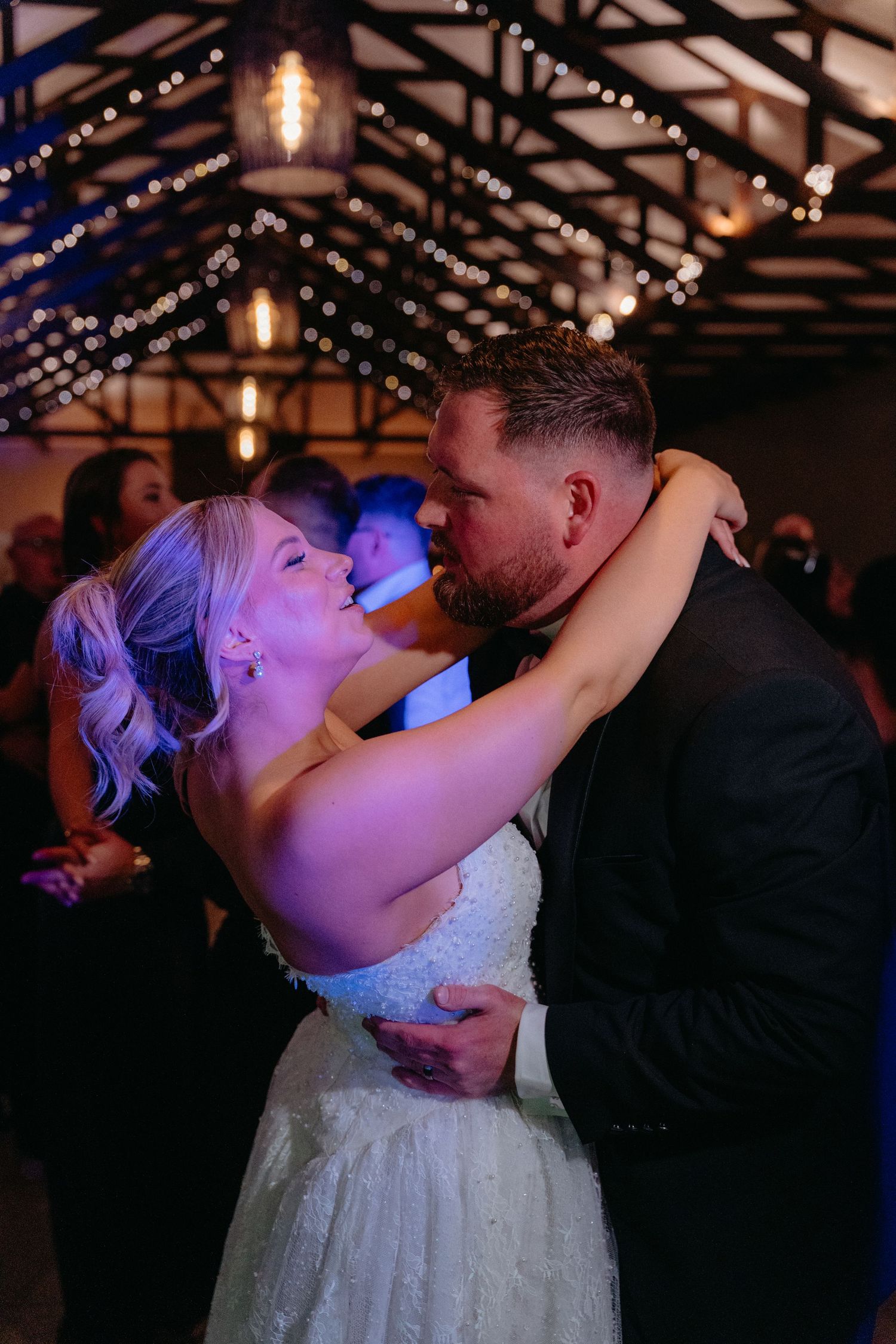 Romantic wedding dance sequence showing couple sharing intimate moments under twinkling lights in rustic venue.