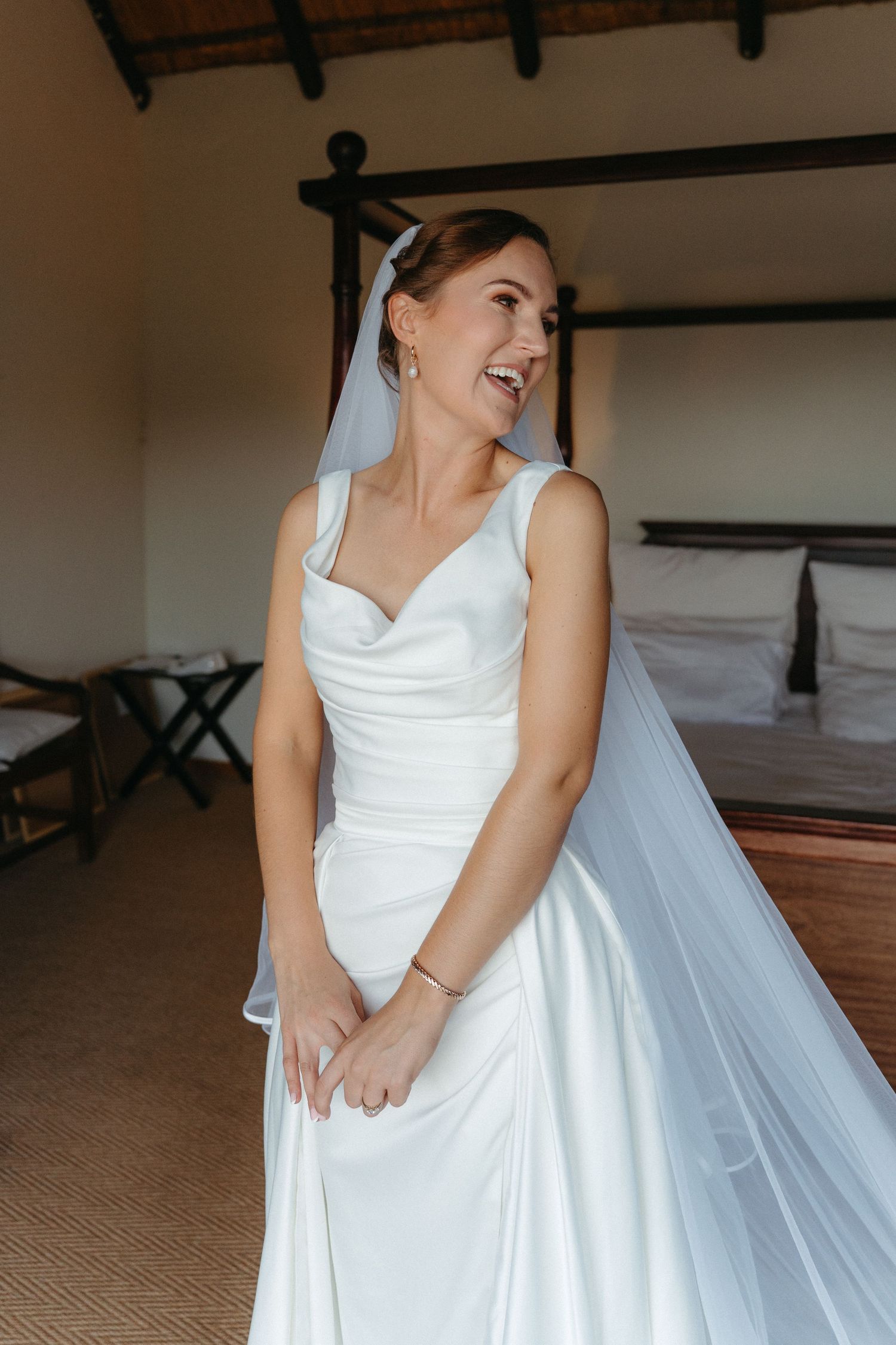 Elegant white wedding dress with flowing fabric and v-neckline photographed in natural light indoors.