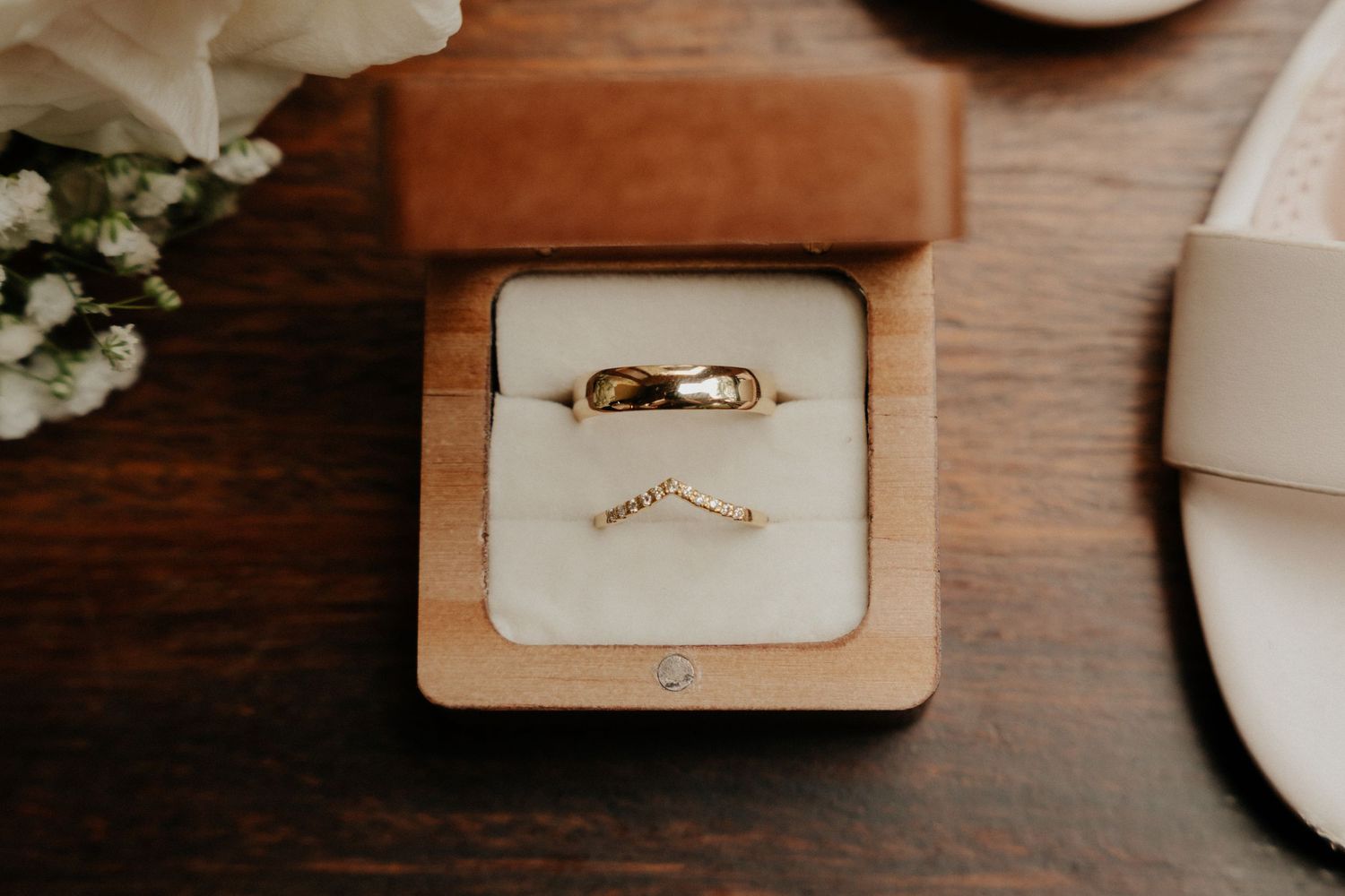 Wedding rings displayed in wooden boxes on rustic table setting.