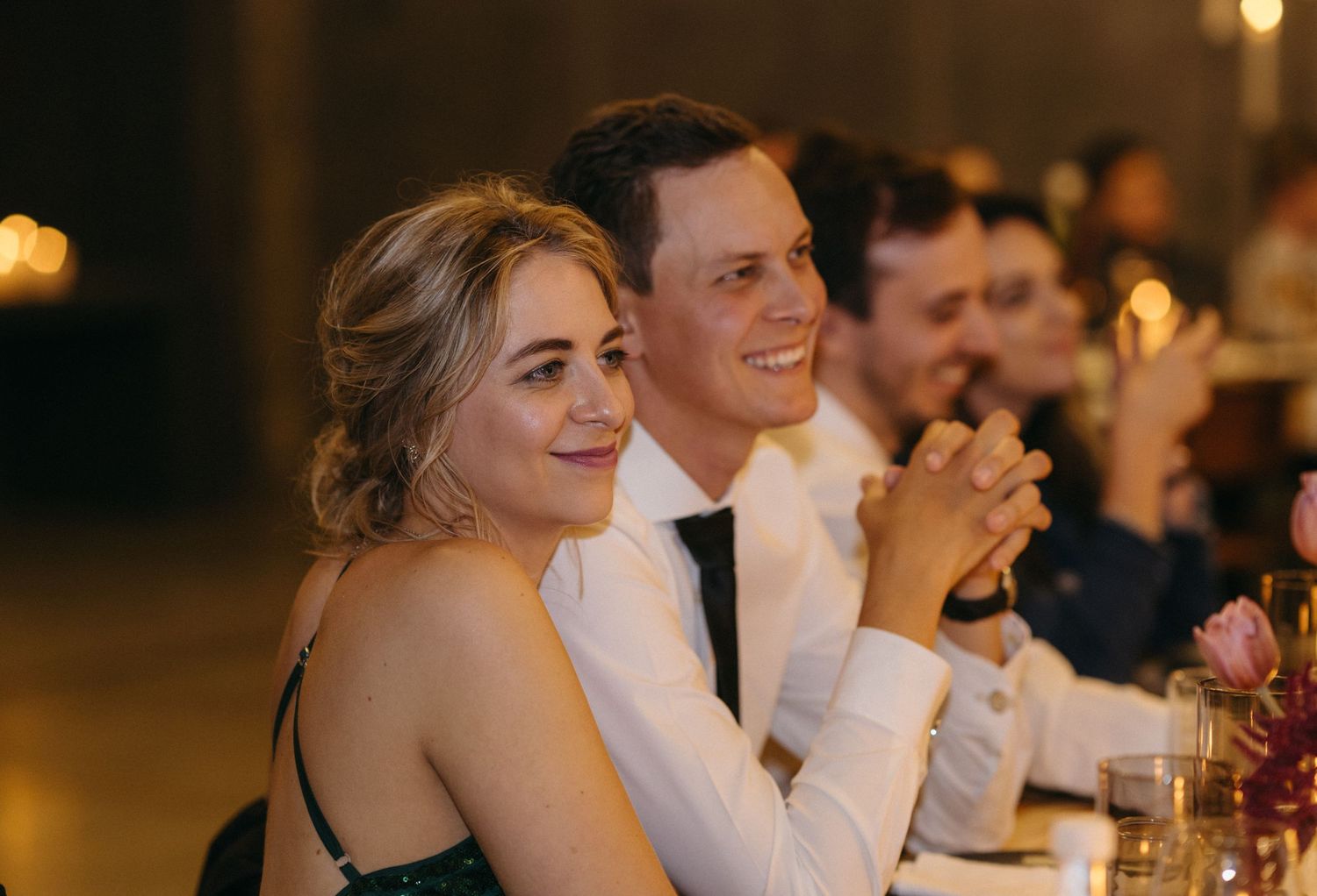 Wedding guests applaud during reception at elegantly decorated venue.
