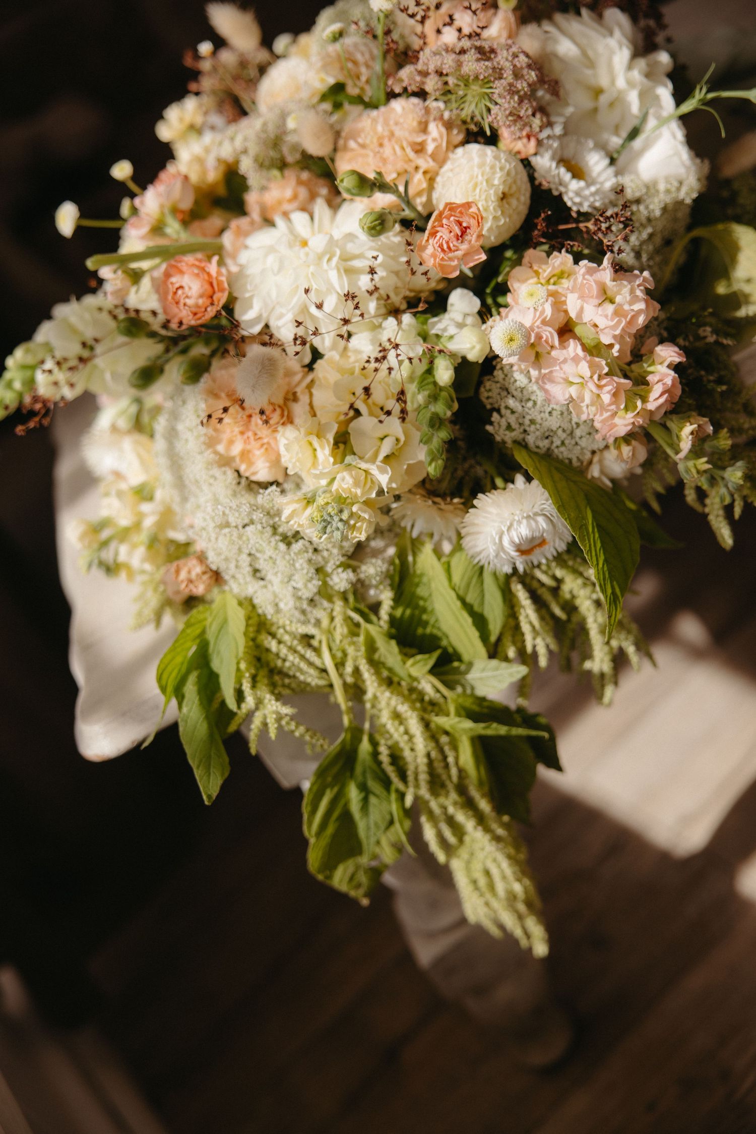 Lush bridal bouquet featuring white hydrangeas, peach roses, and cascading greenery in warm natural light at Kasteelkop Guest Farm