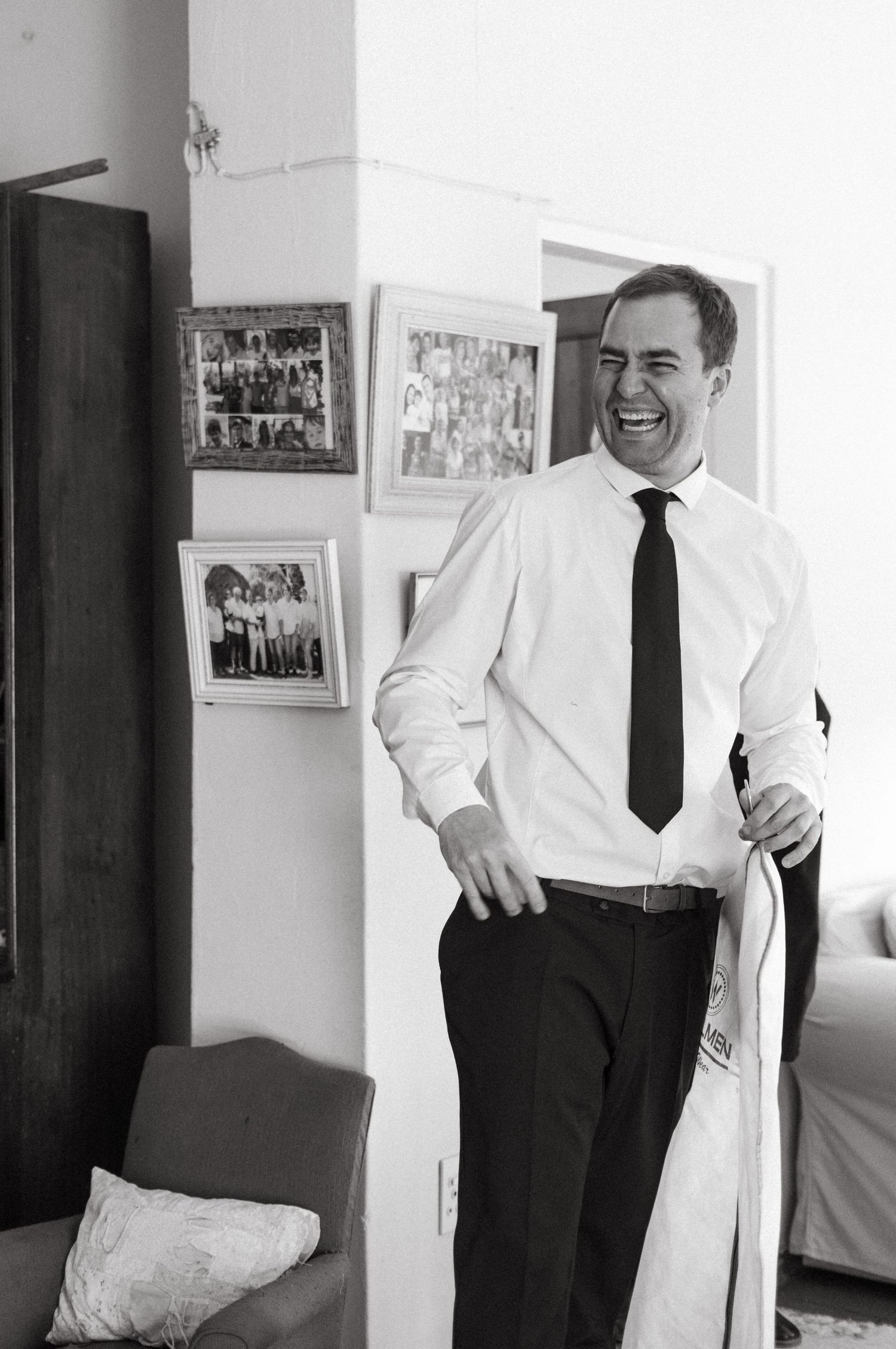 A joyful moment captured in black and white showing someone laughing while wearing a white dress shirt and black tie.