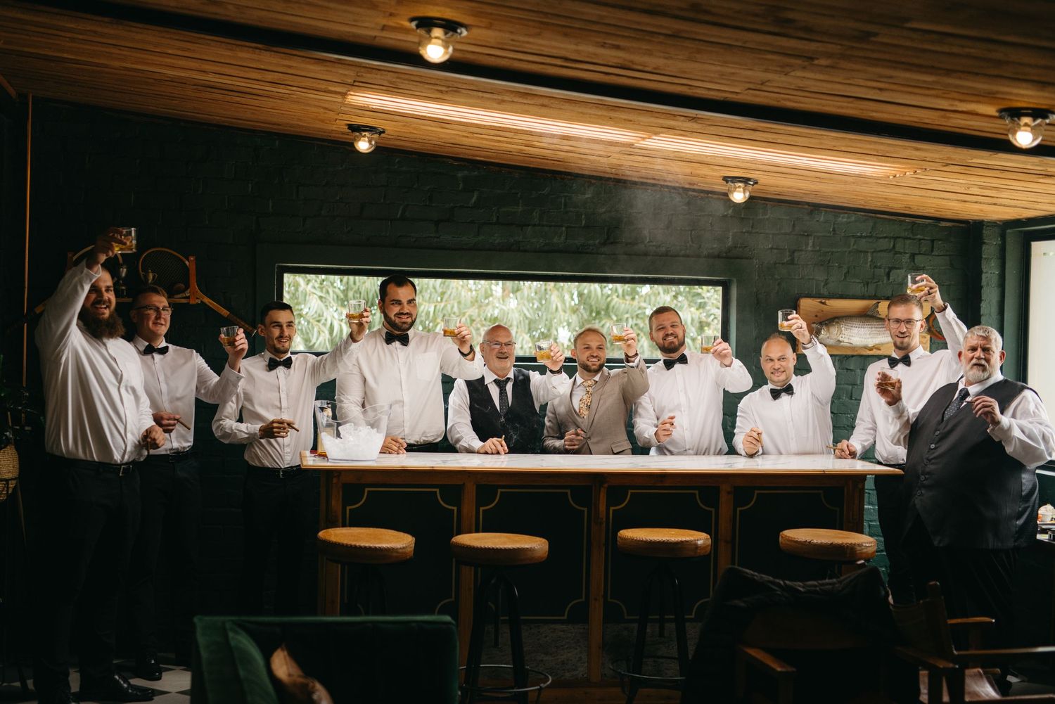 Group in white dress shirts gather at a wooden bar under warm overhead lighting.