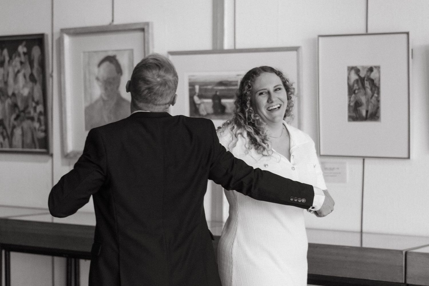 A couple shares a tender dance moment in a gallery surrounded by artwork.