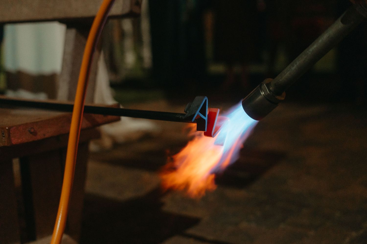 A close-up shot of a blue flame torch in action against a dark background.