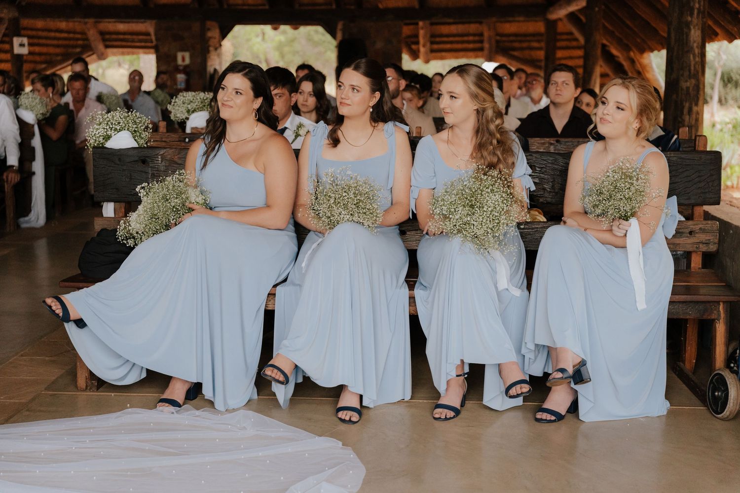 A group wearing matching light blue dresses stands together in a wooden barn-style venue.