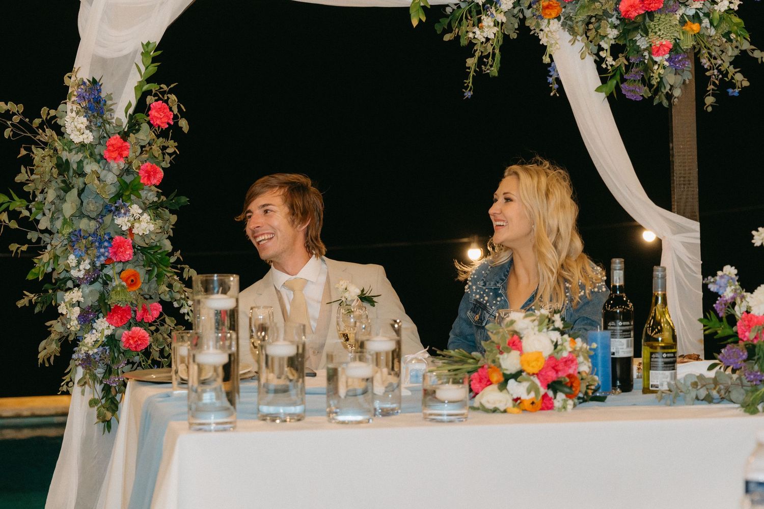 Wedding reception dinner setup with elegant floral centerpieces and string lights creating a romantic ambiance.