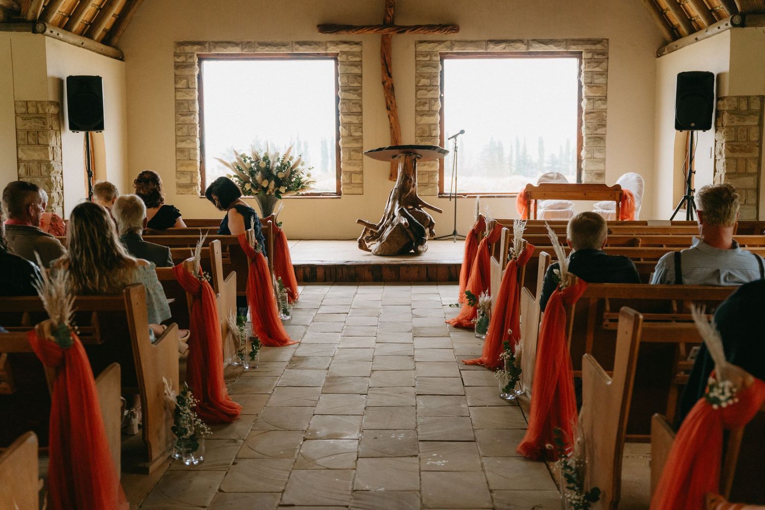 Church interior decorated with red fabric on pews and wooden cross at the altar.