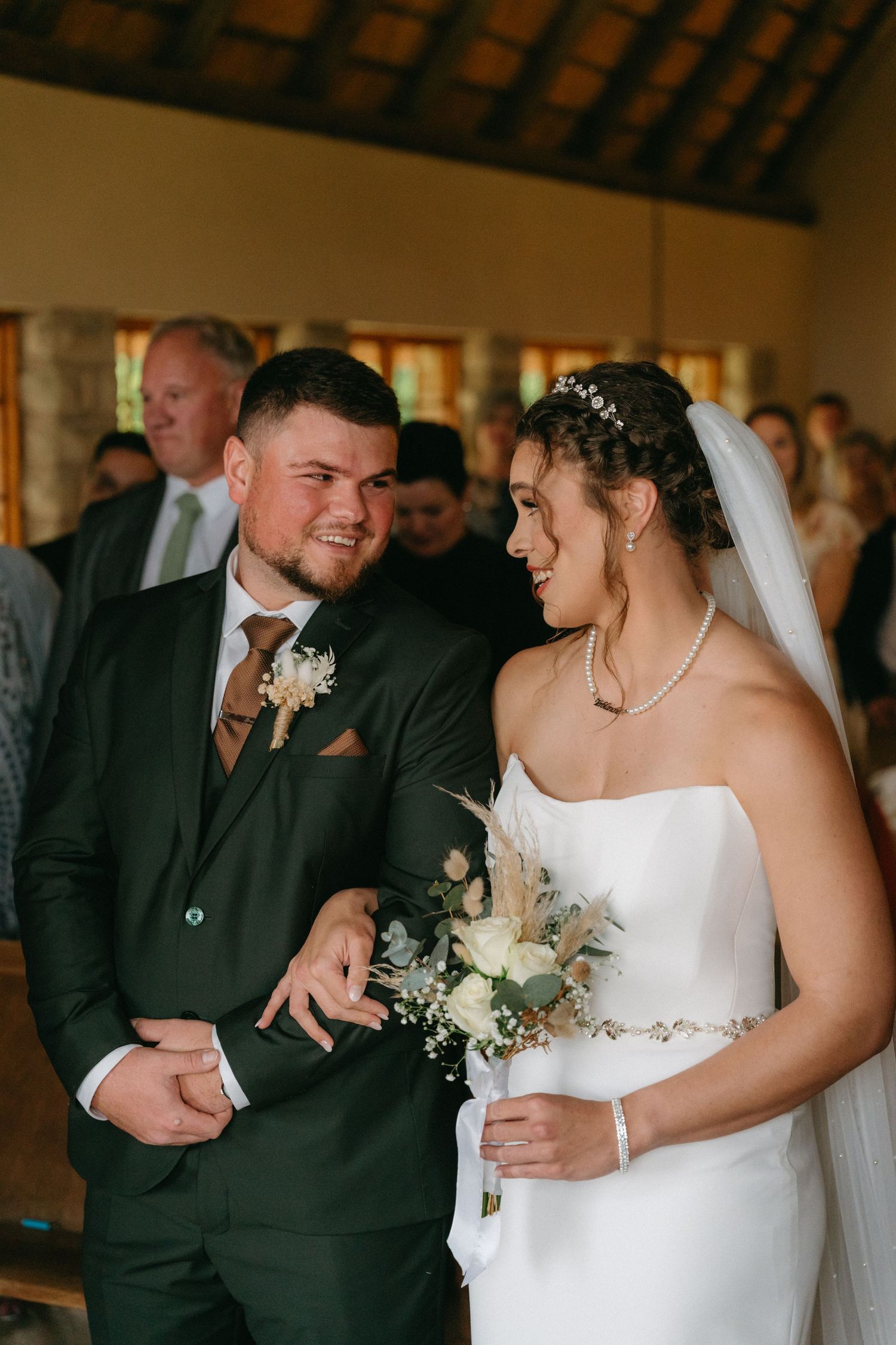 Candid moments between wedding couple during indoor ceremony.