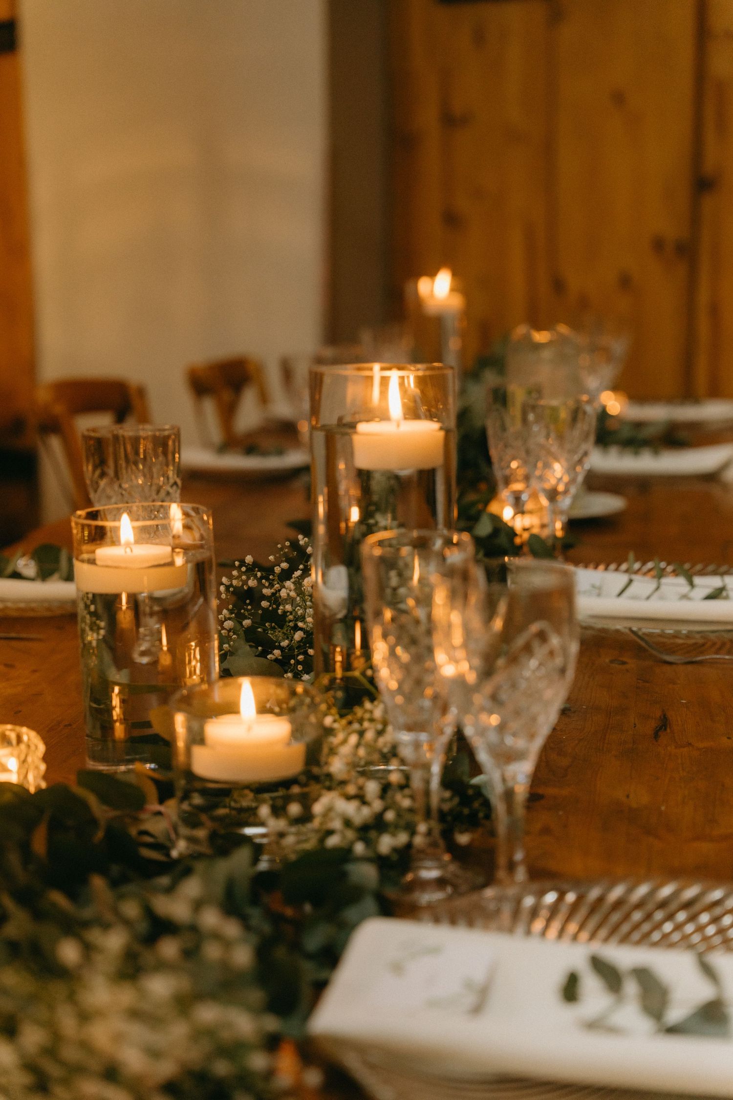 Elegant table setting with glowing candles and greenery garlands for a wedding reception.