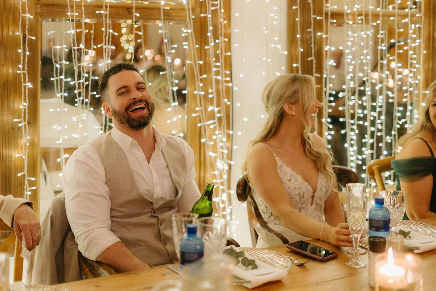 Wedding reception tables decorated with hanging fairy lights and wooden accents.