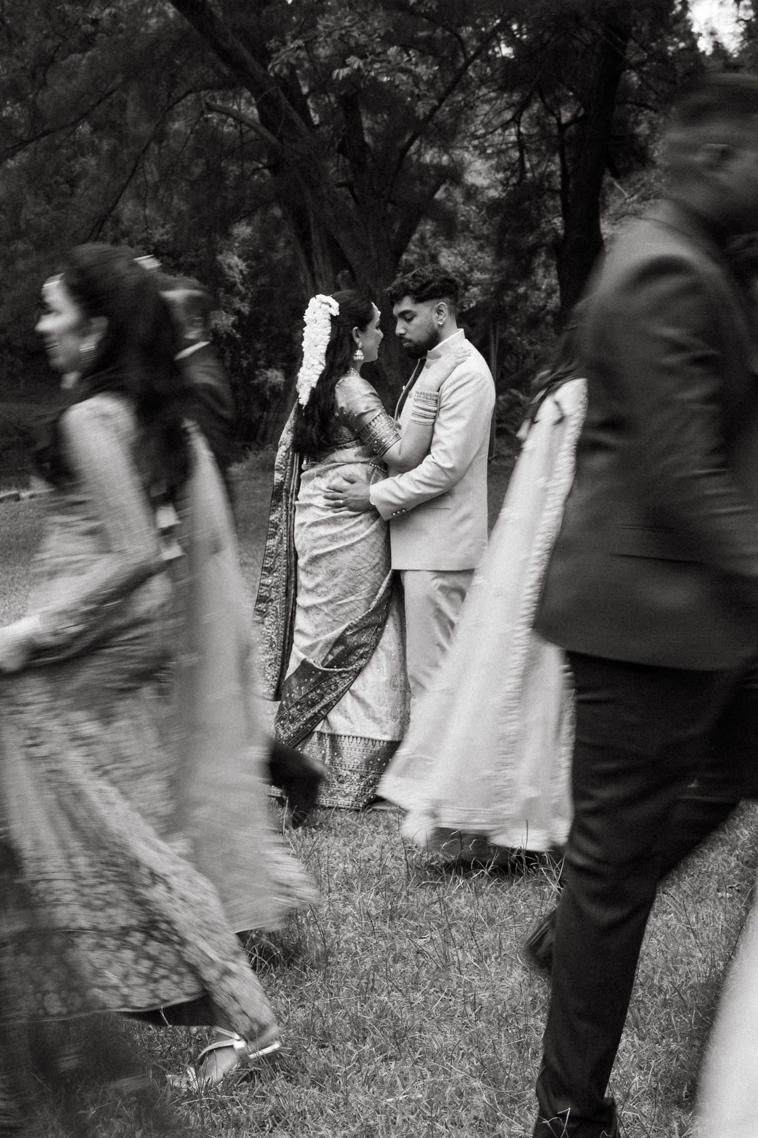 Motion blur captures a couple dancing together on grass in black and white photography.