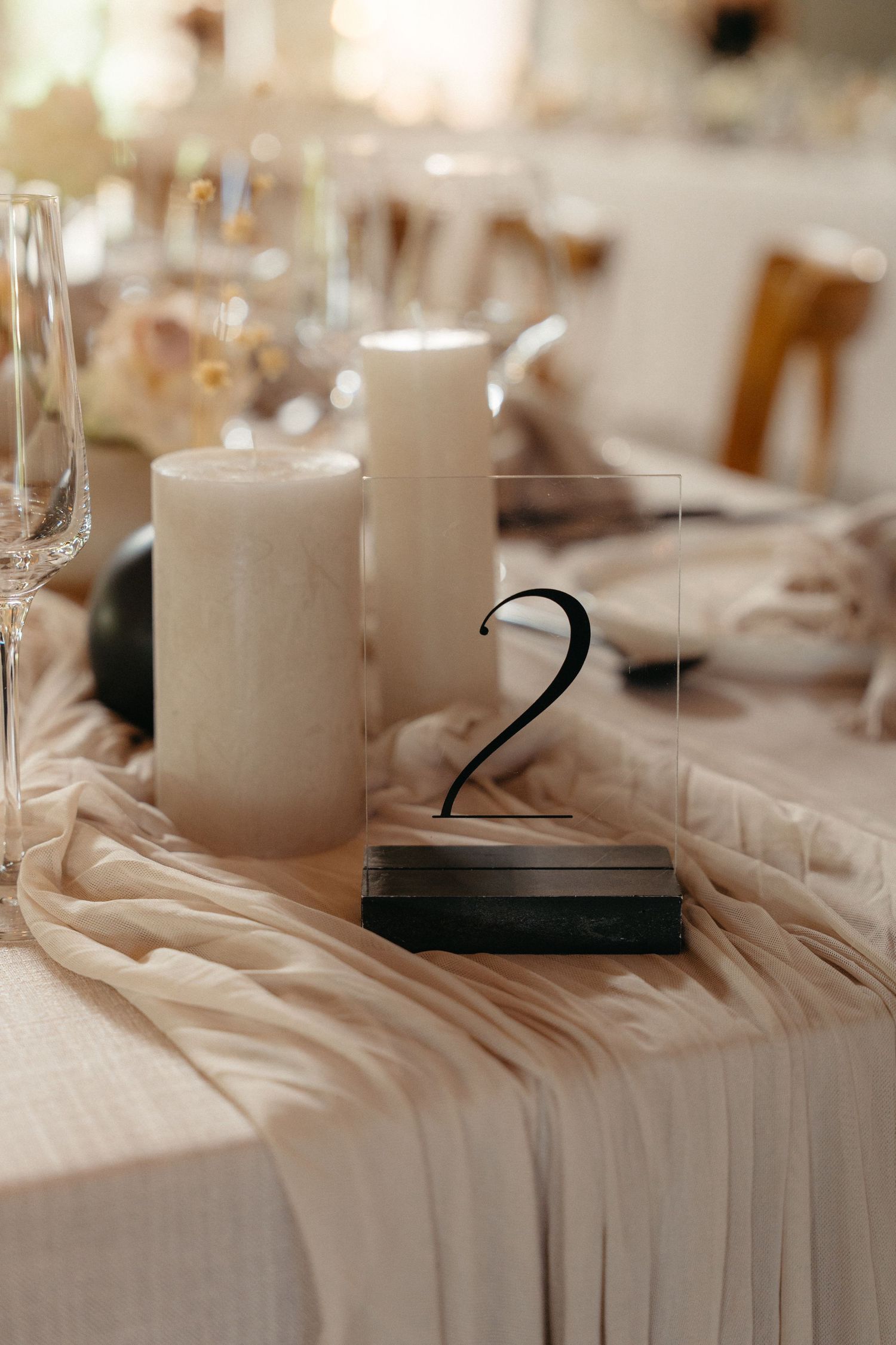 White table settings with elegant candle centerpieces in a soft focus wedding reception setup.