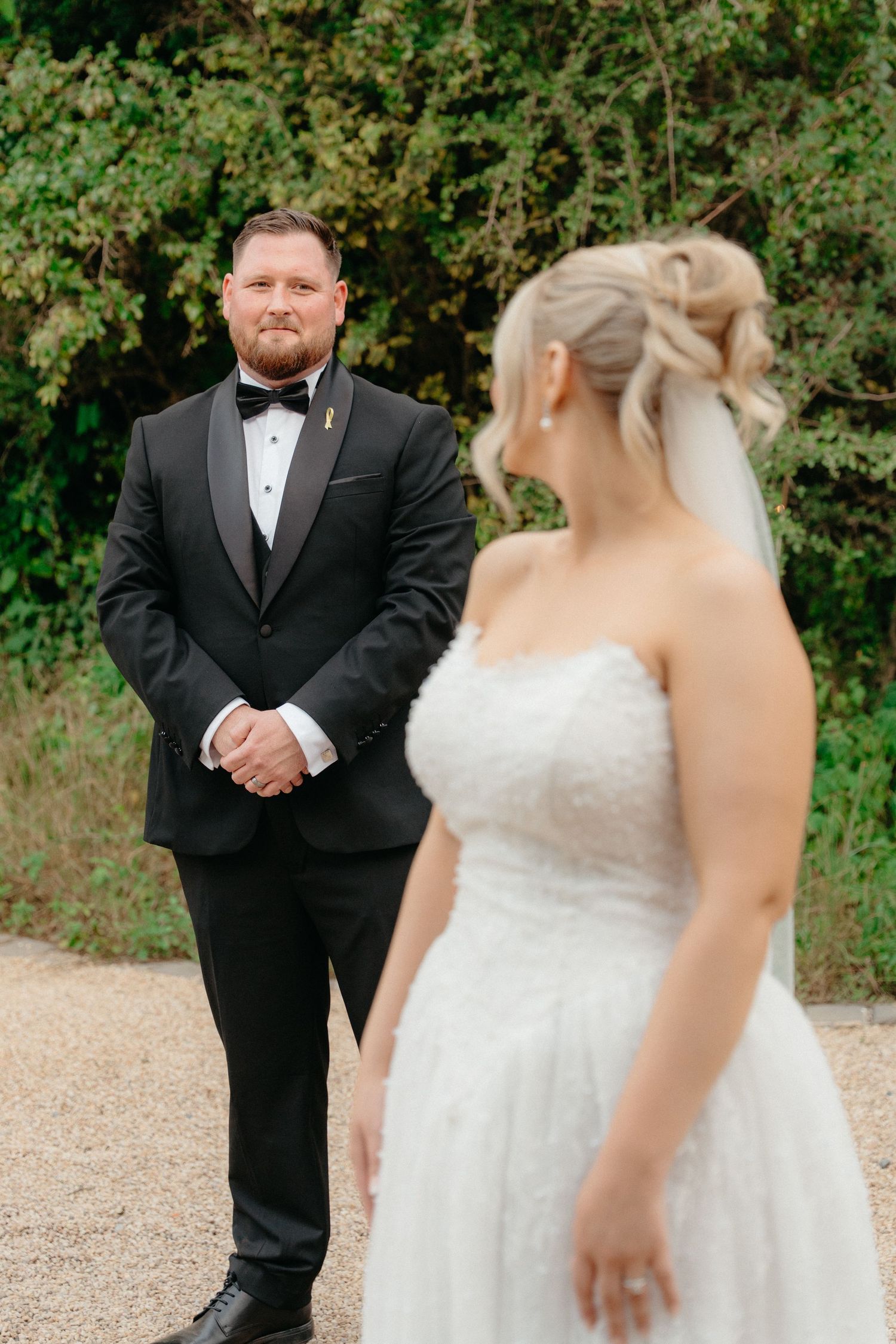 A wedding first look sequence showing a bride and groom sharing an emotional moment on a gravel path surrounded by greenery.