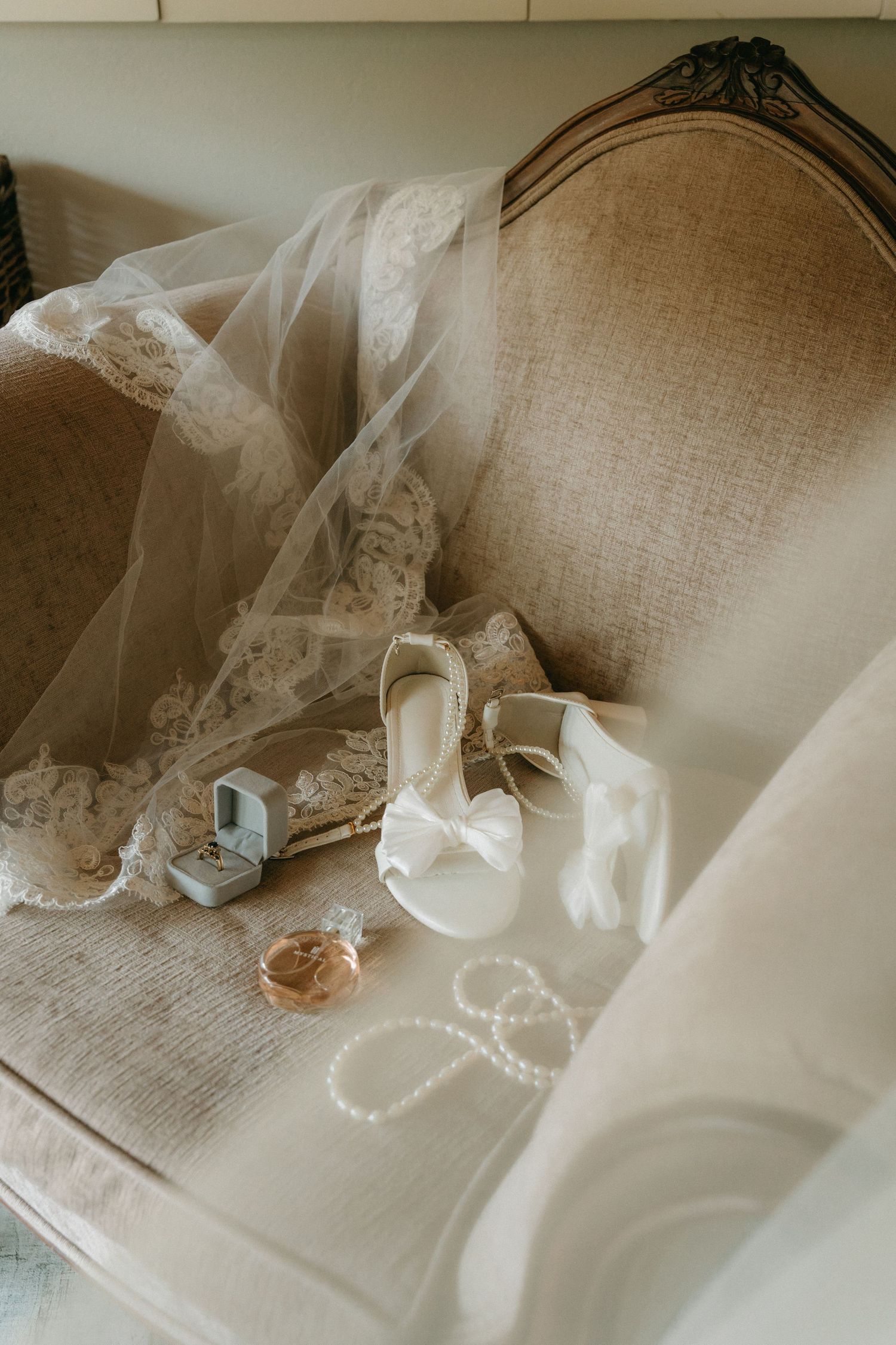 Bridal accessories arranged on vintage chair at Cradle Valley Lodge including white heels, veil, pearls, and ring box.