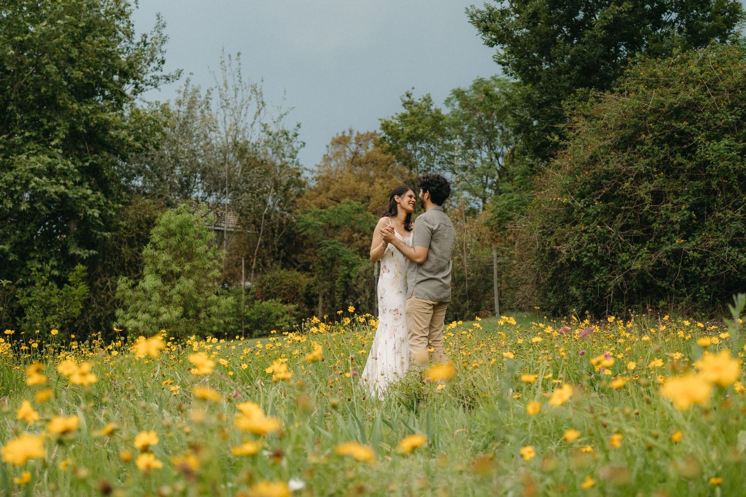 A couple embraces in a meadow filled with yellow wildflowers in their Gauteng engagement photo session