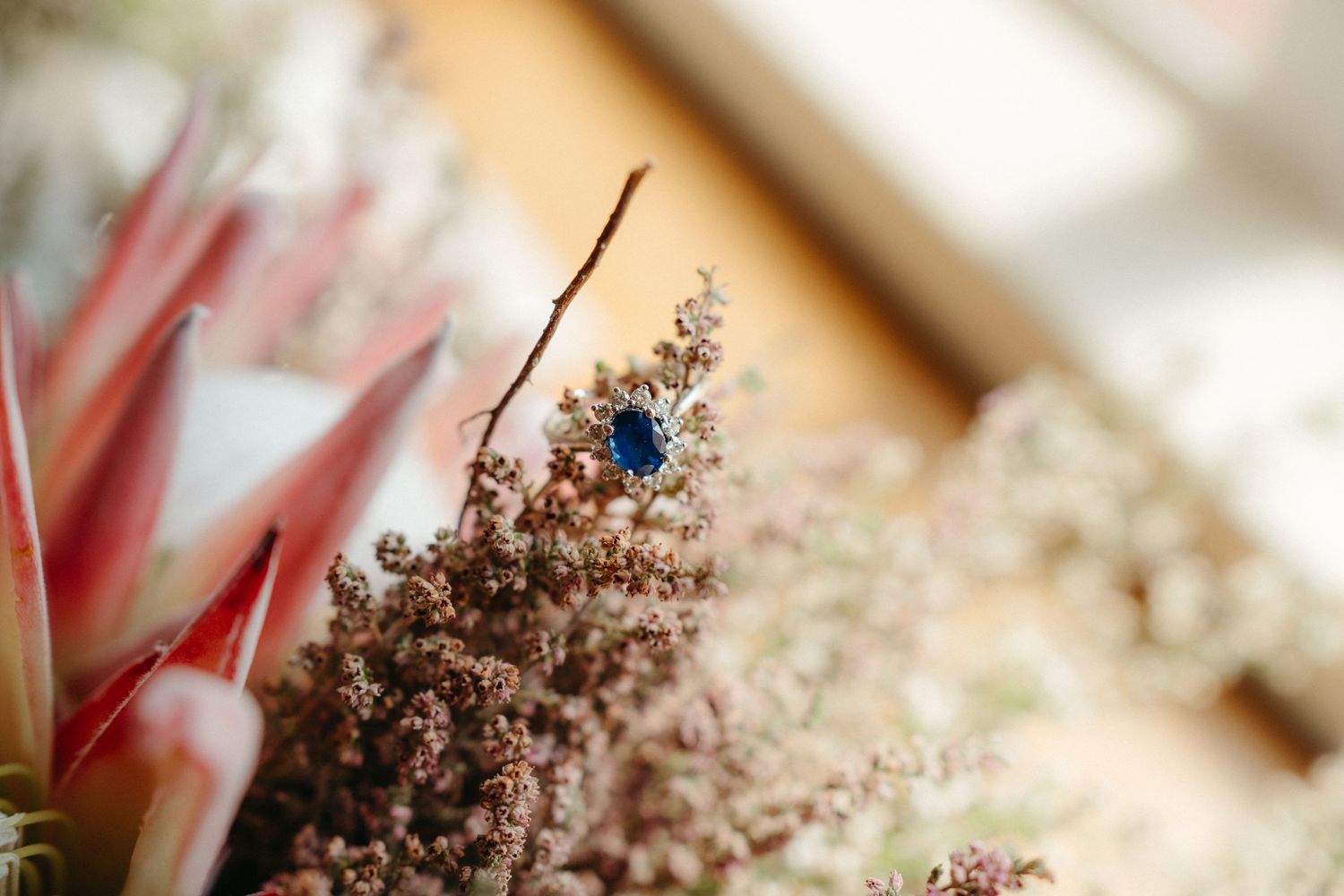 Close-up of a blue gemstone detail among dried brown flowers and foliage.