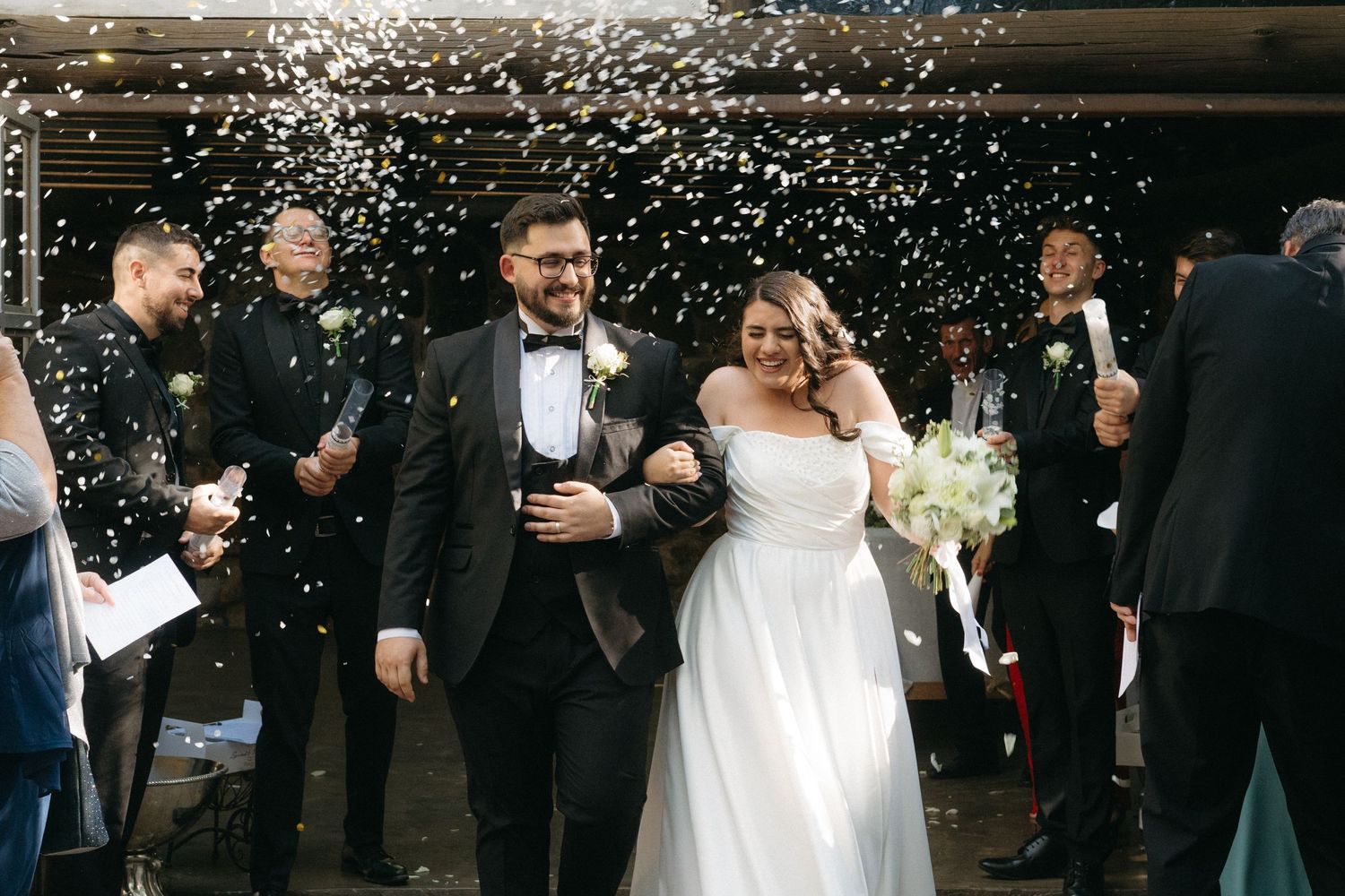 Newlyweds walk together under a shower of confetti and sparkles at their joyful outdoor wedding celebration.