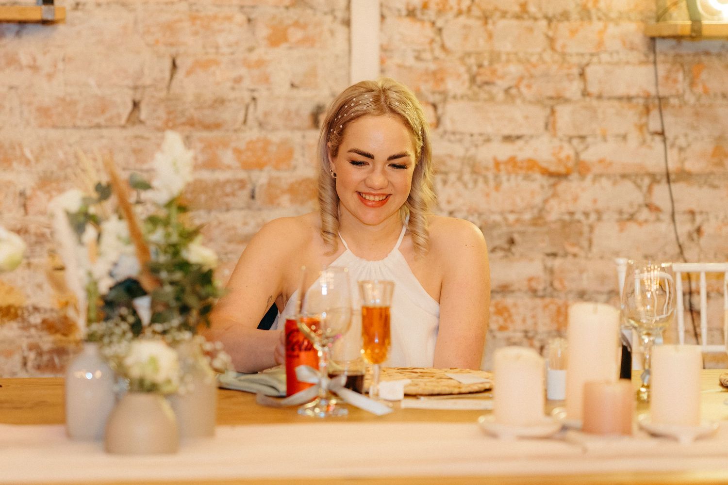 Someone enjoying dinner at a rustic restaurant with brick walls, candlelight and elegant table settings.