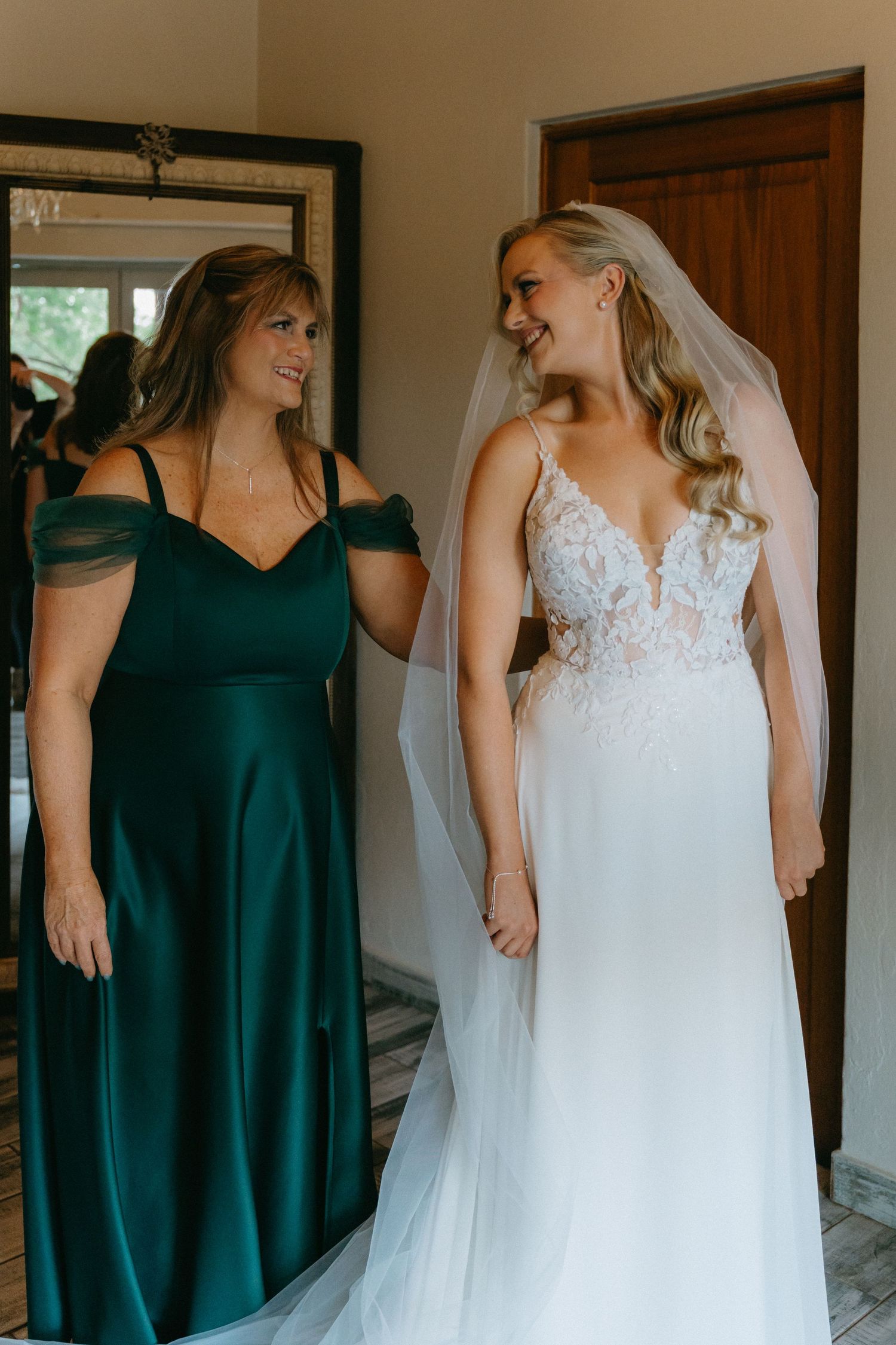 Wedding party getting ready in emerald green dresses and white lace gown.