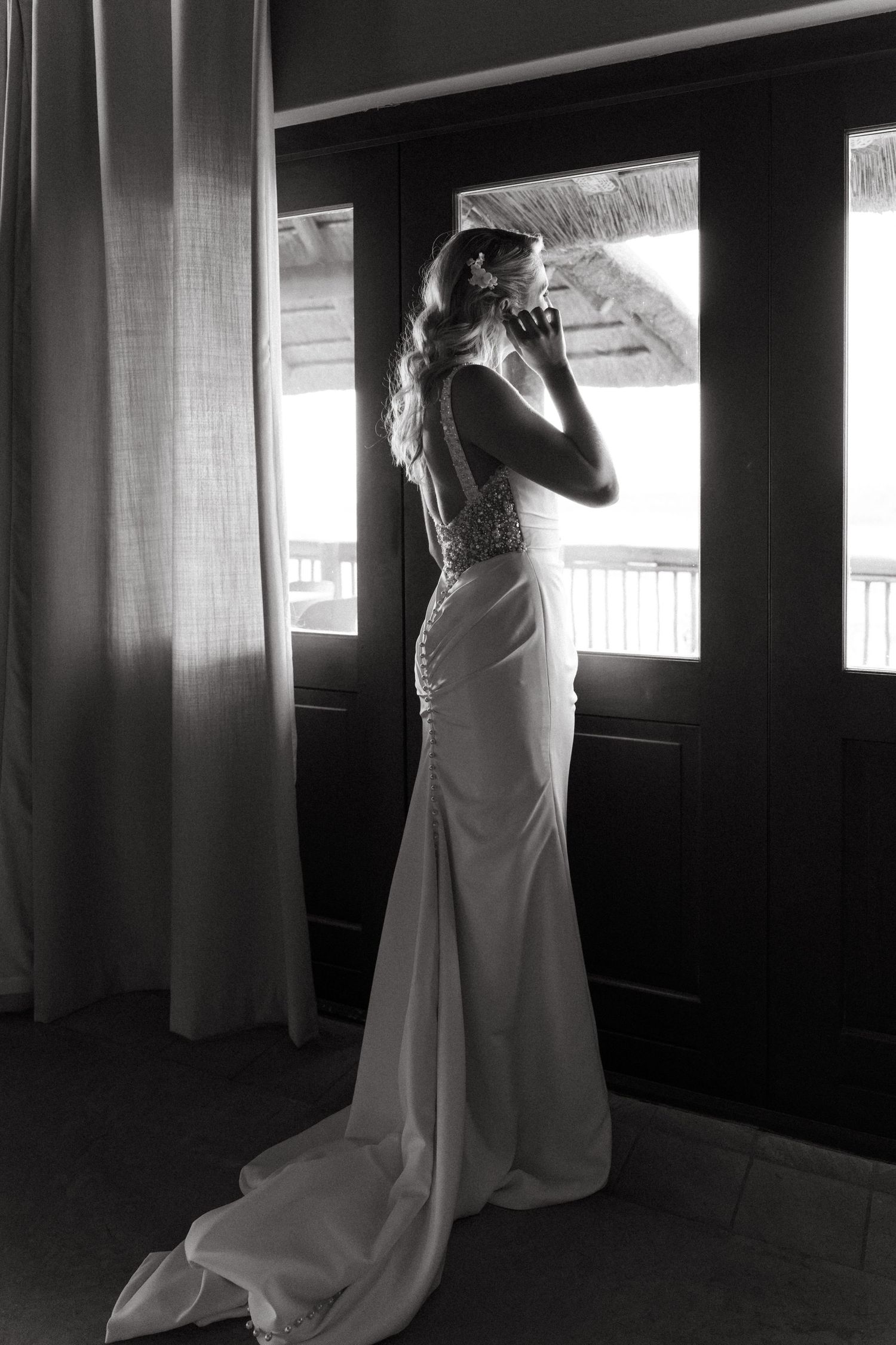 A dramatic black and white photo series of a wedding dress being fitted in a dimly lit room.