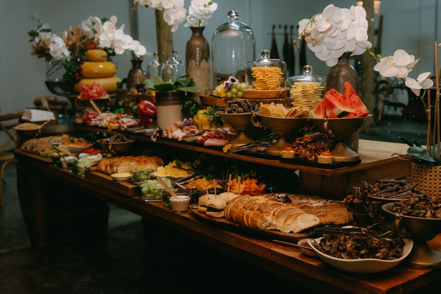 Elegant wedding reception buffet table with diverse food displays and decorative settings.