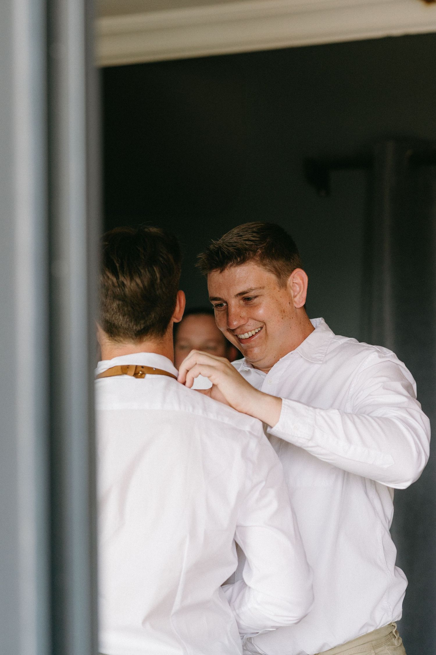 Two people in white dress shirts share a warm embrace and joyful moment together indoors.