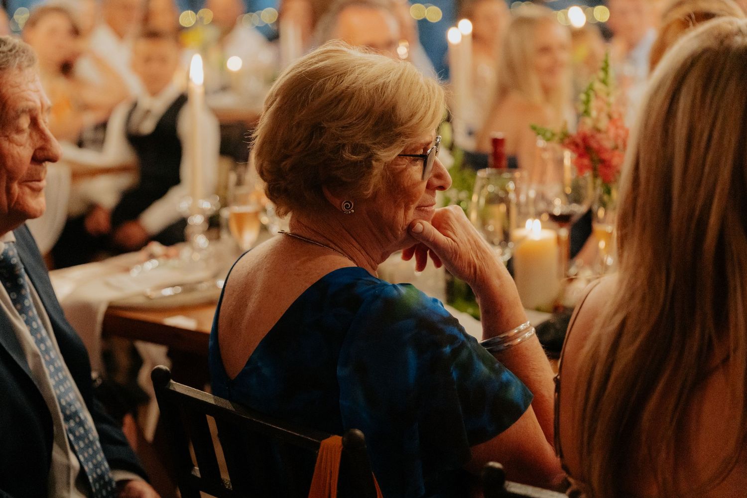 Guests enjoying conversation at an elegant dinner reception with wine glasses and ambient lighting.