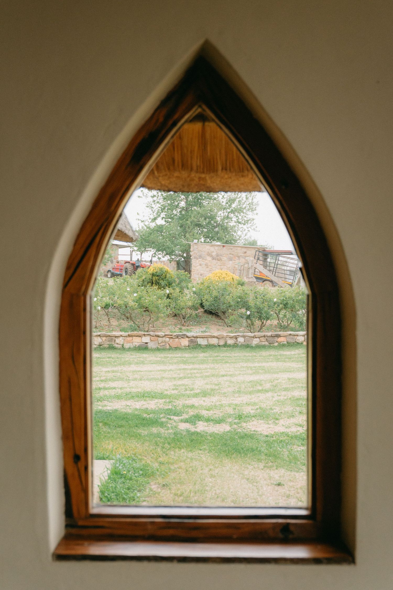Series of gothic-style arched windows with wooden frames overlooking a rural landscape.