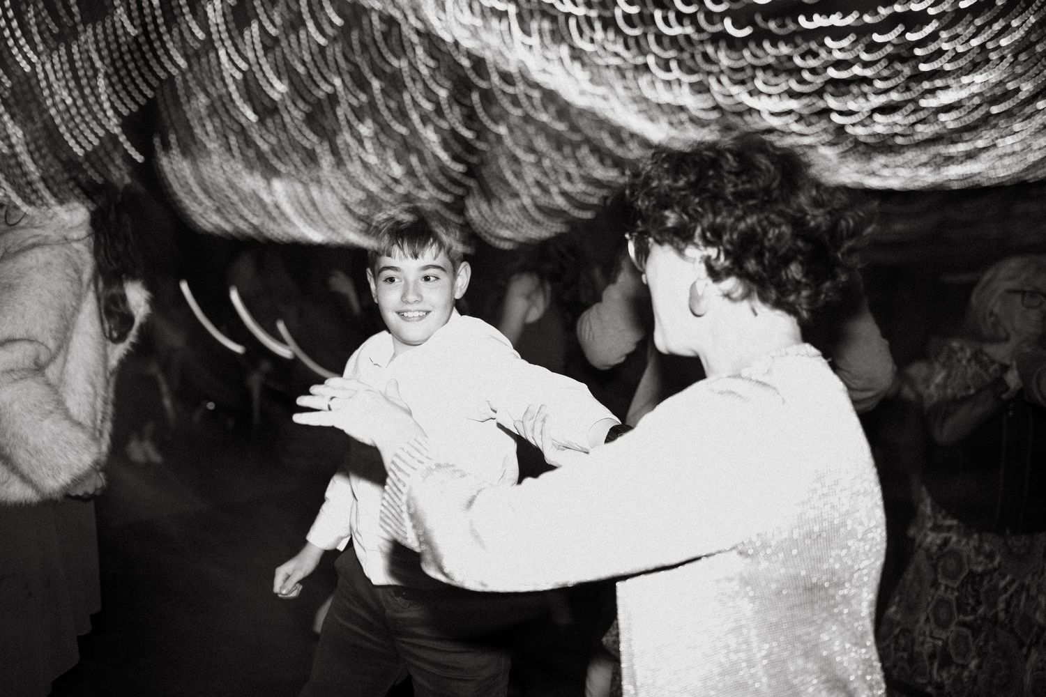 Black and white photo of a child being lifted by an adult at a festive indoor event.