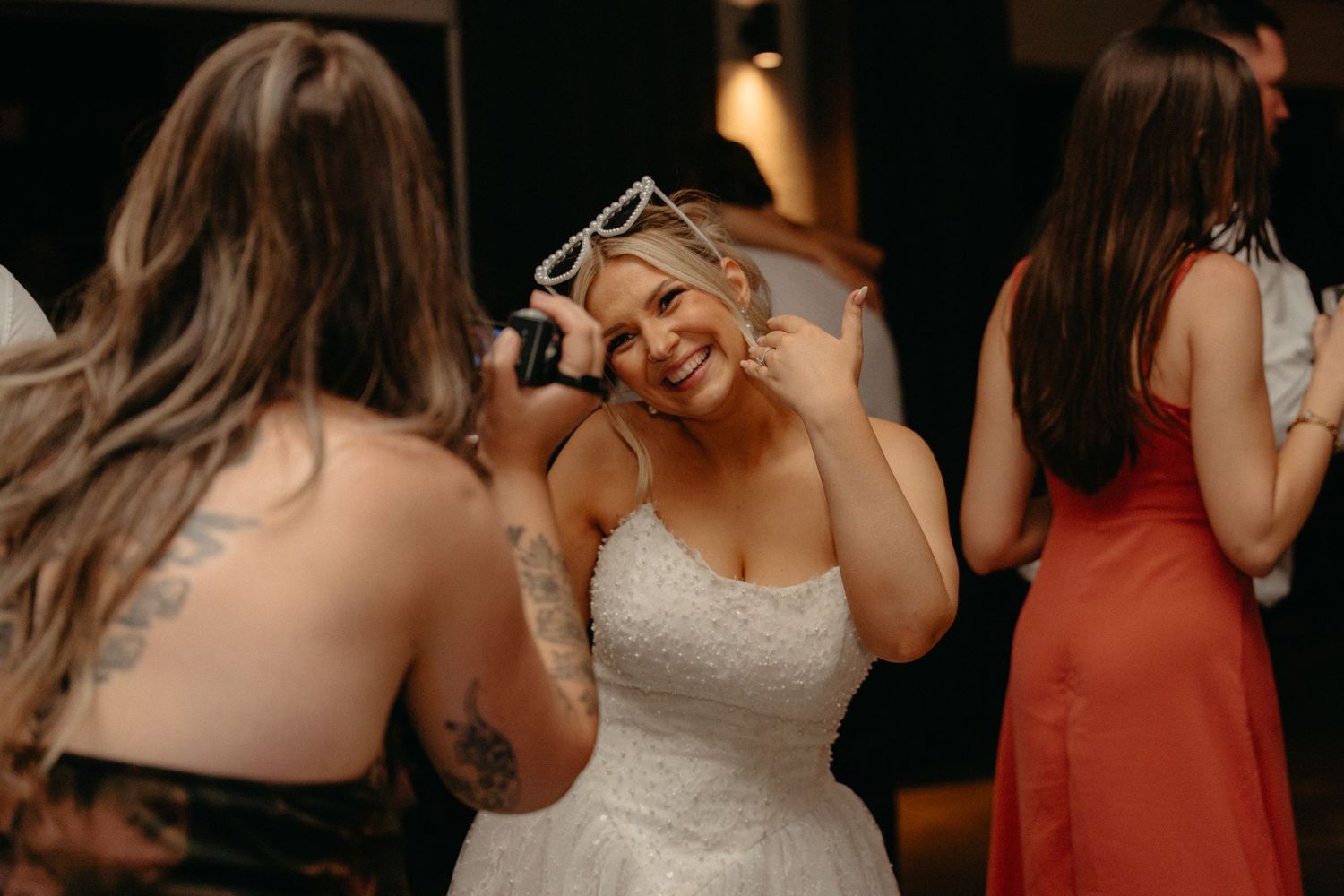 A person in a white wedding dress dances and smiles on the dance floor during a reception celebration.