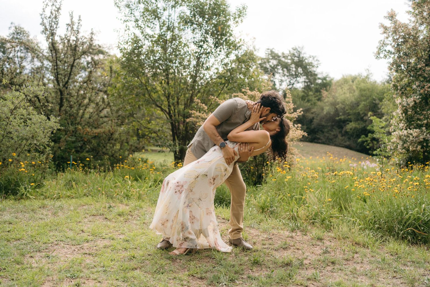 Romantic dip pose in a flowery summer meadow with flowing dress.