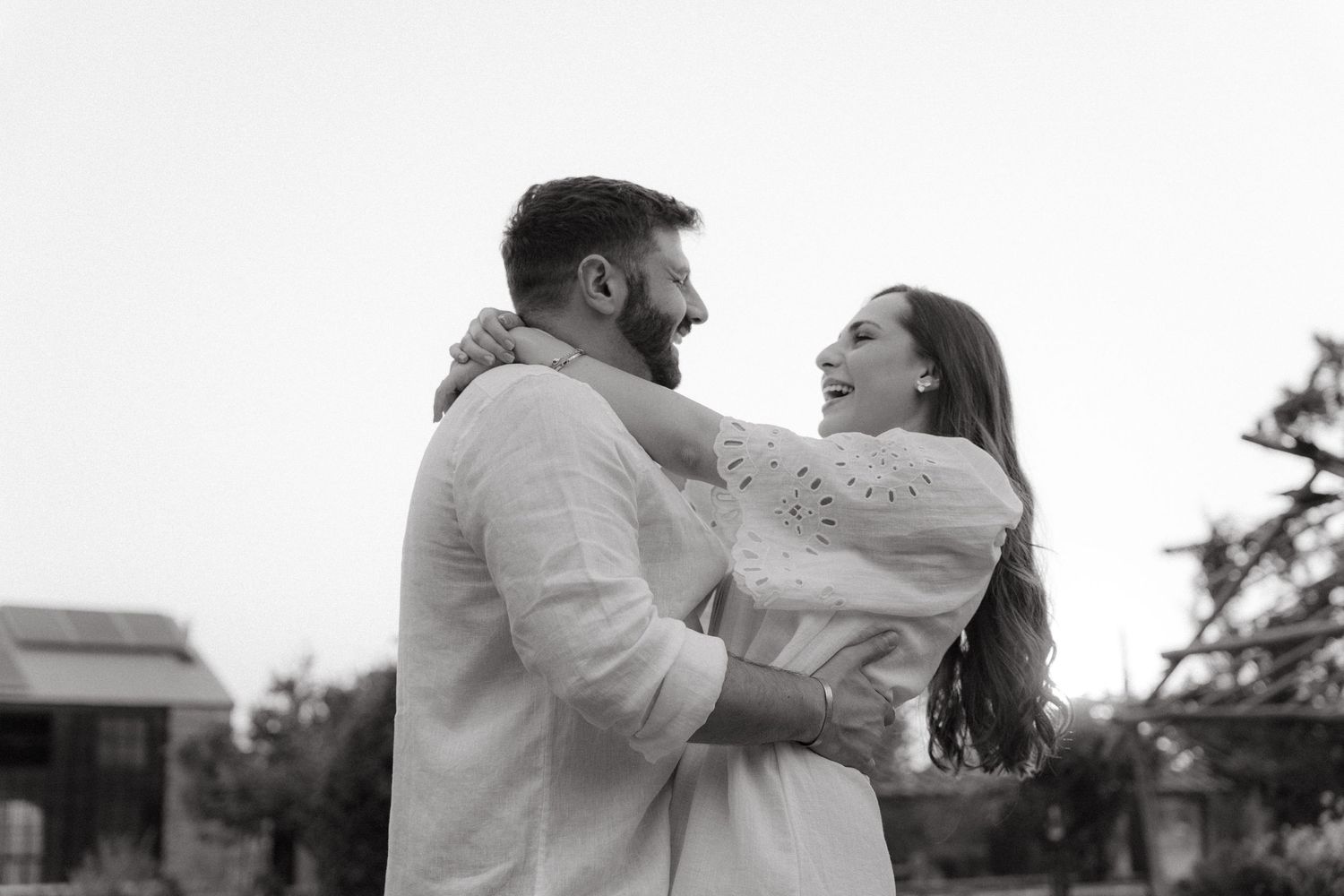 Couple in white outfits embracing outdoors during a romantic photoshoot.
