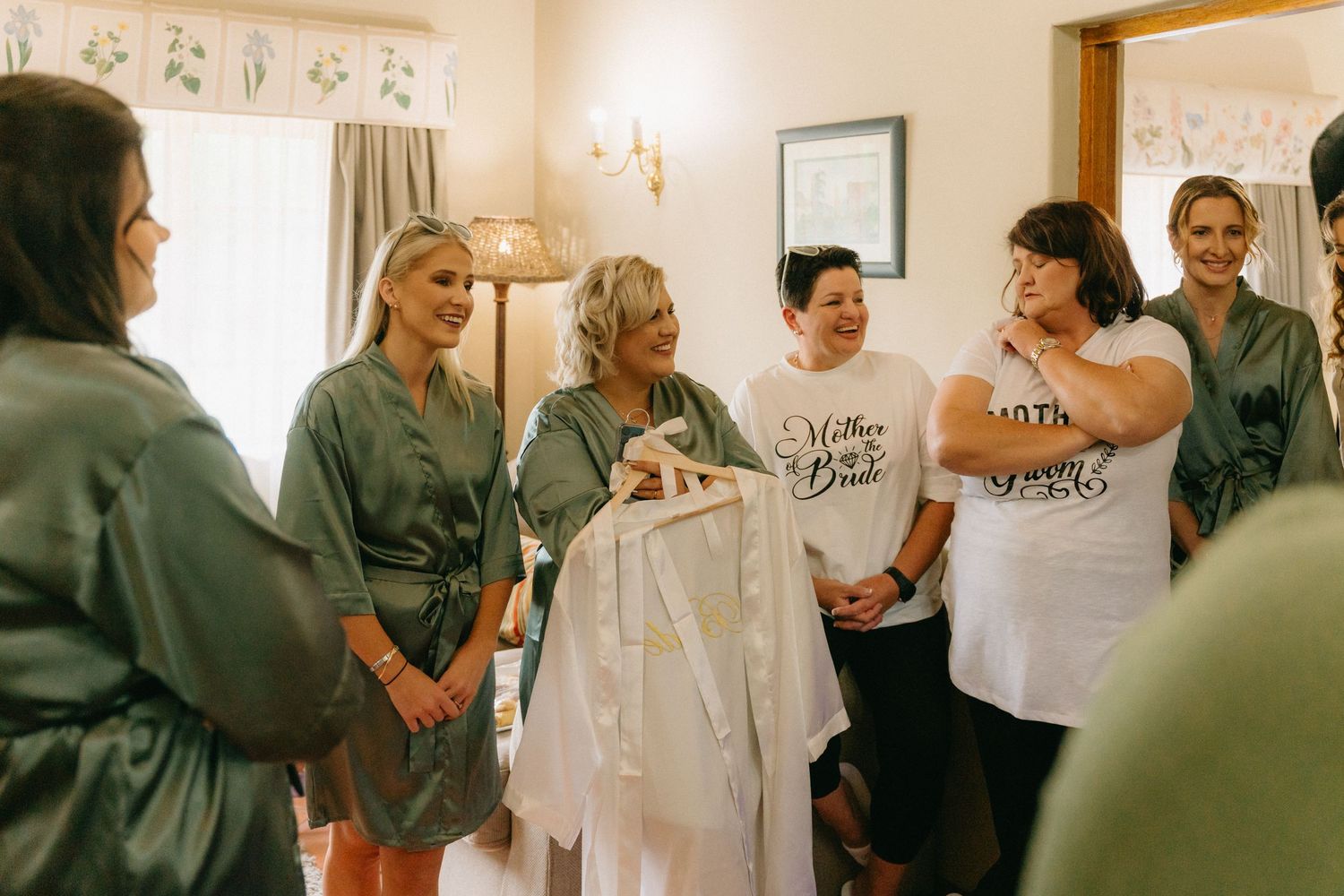 Wedding party members gather in a bright indoor space during pre-ceremony preparations.