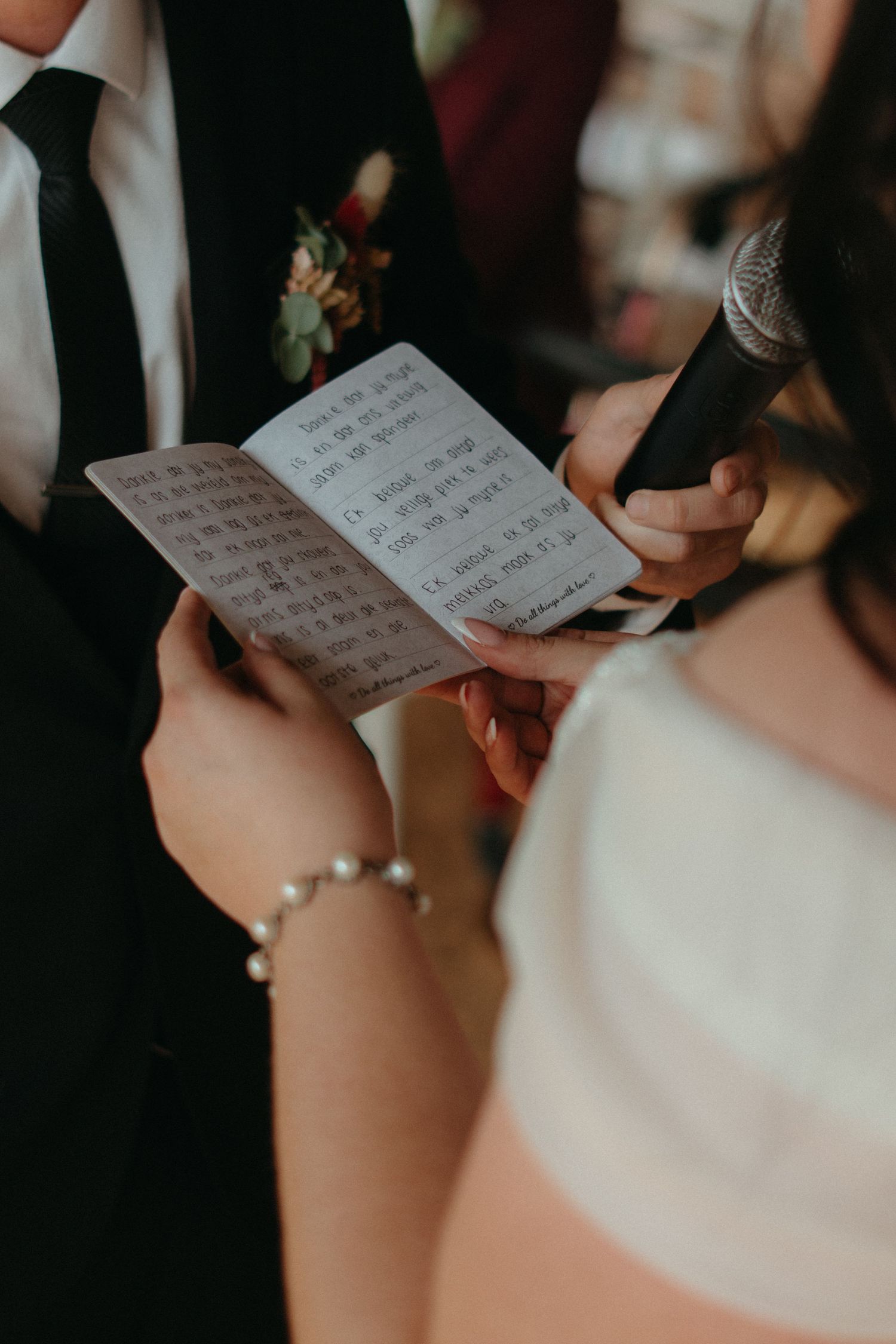 Close-up of hands holding handwritten wedding vows during ceremony.
