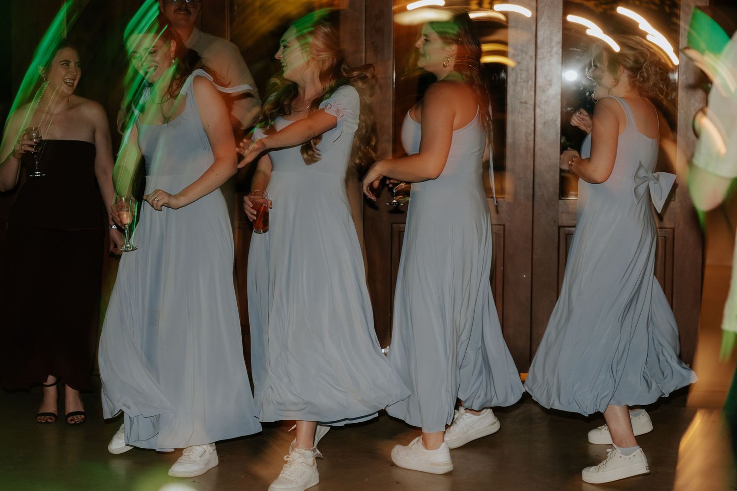 Bridesmaids in light blue dresses dancing together at a wedding reception.