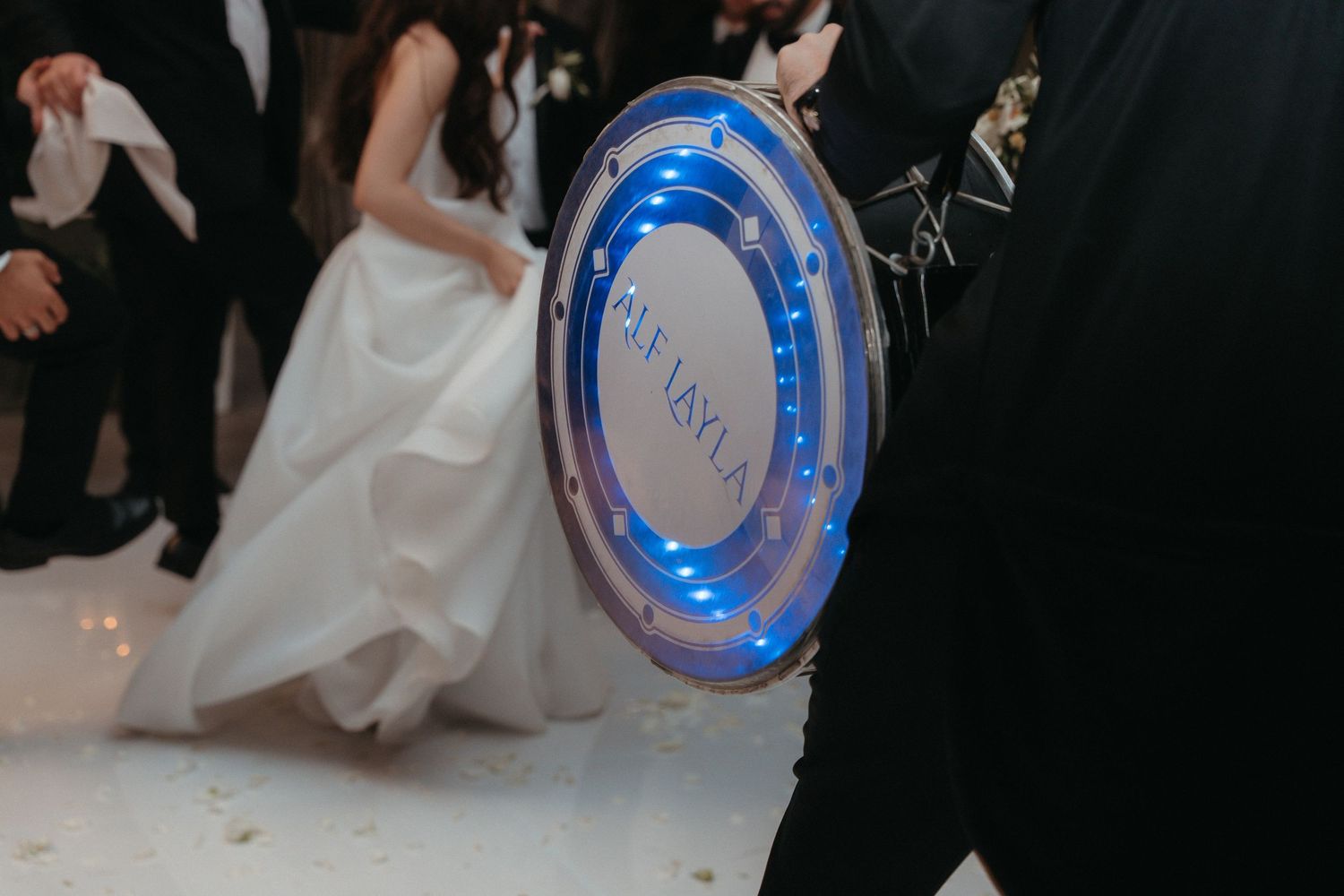 Illuminated wedding monogram sign with blue LED lights displayed on dance floor during reception celebration.