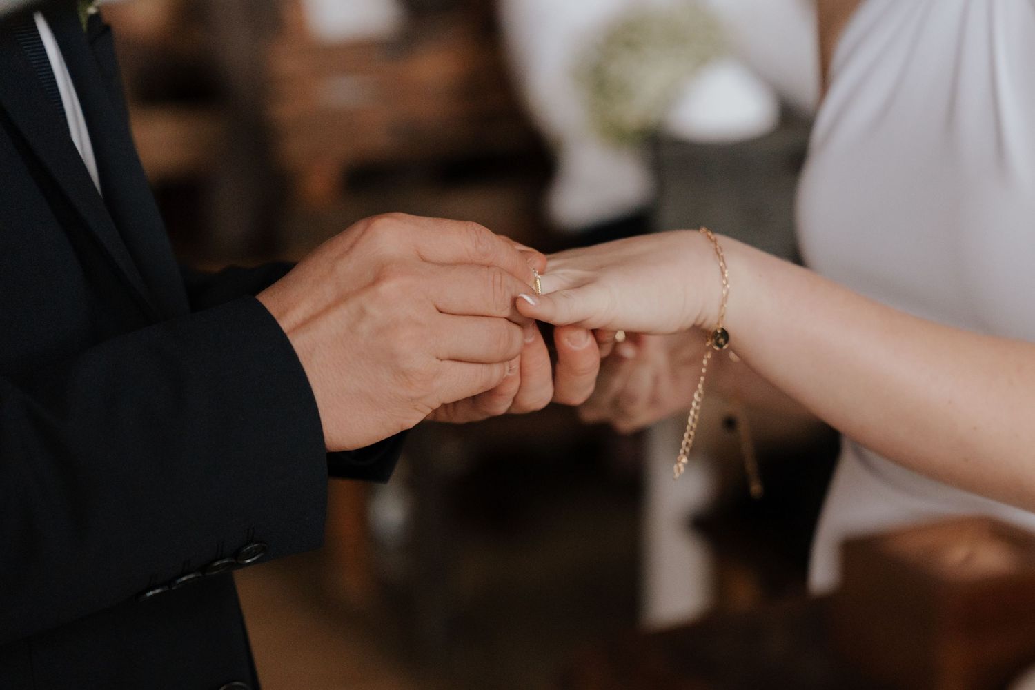Close-up of hands exchanging rings during wedding ceremony.
