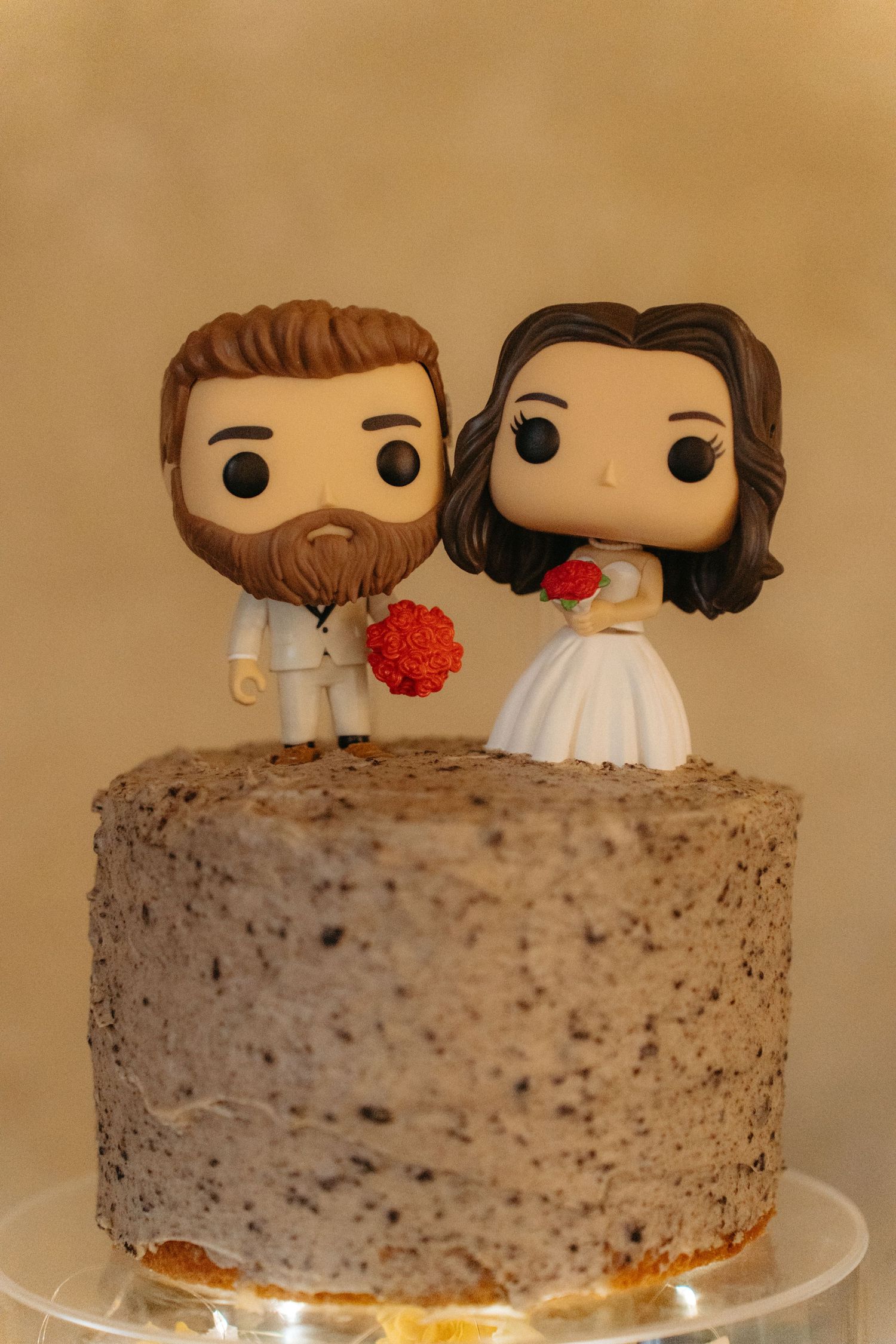 Funko Pop style wedding cake topper featuring bride and groom figurines on a textured gray cake.