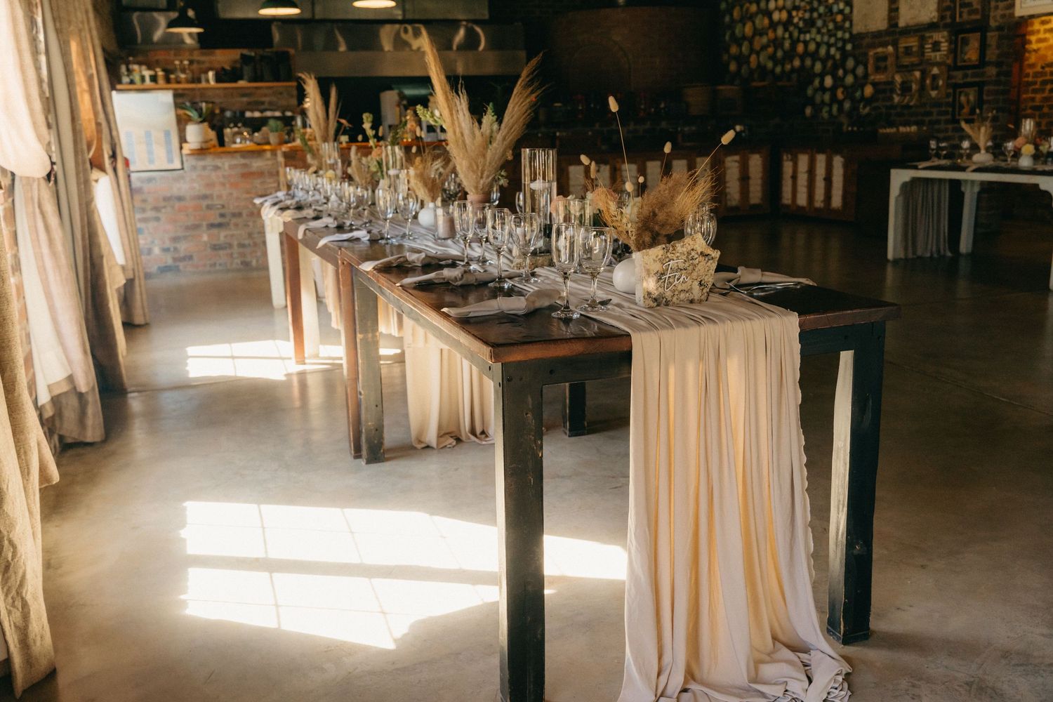 An elegant wedding reception table setup with flowing fabric and place settings in a rustic venue.