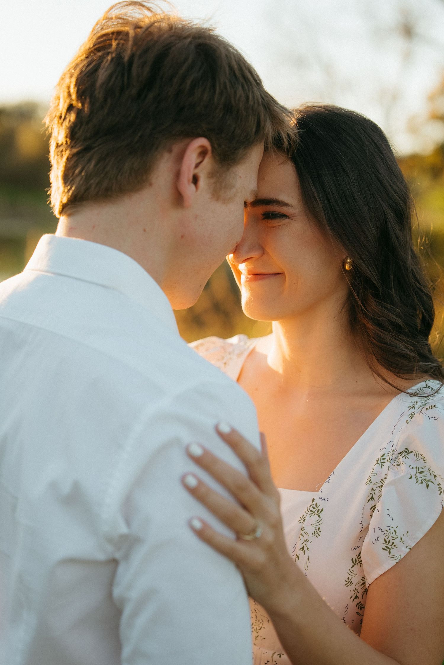 A romantic close-up photo of a couple embracing during golden hour with warm sunlight glowing around them.