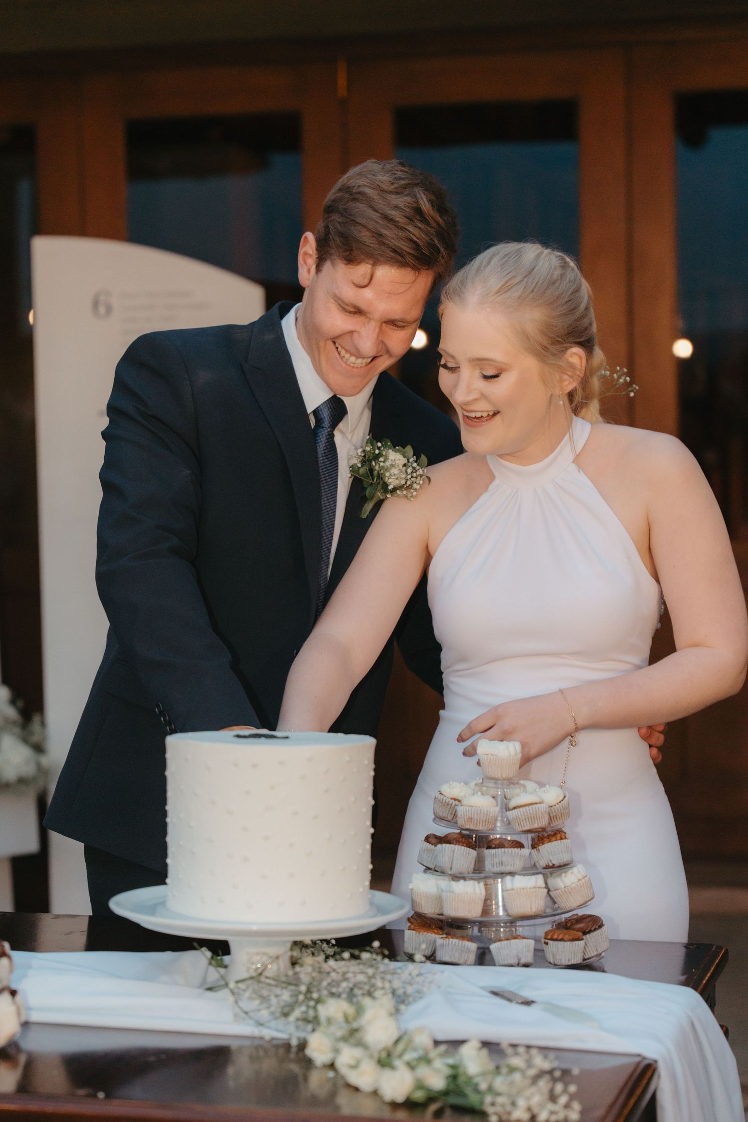 A couple cutting their wedding cake together at their reception.