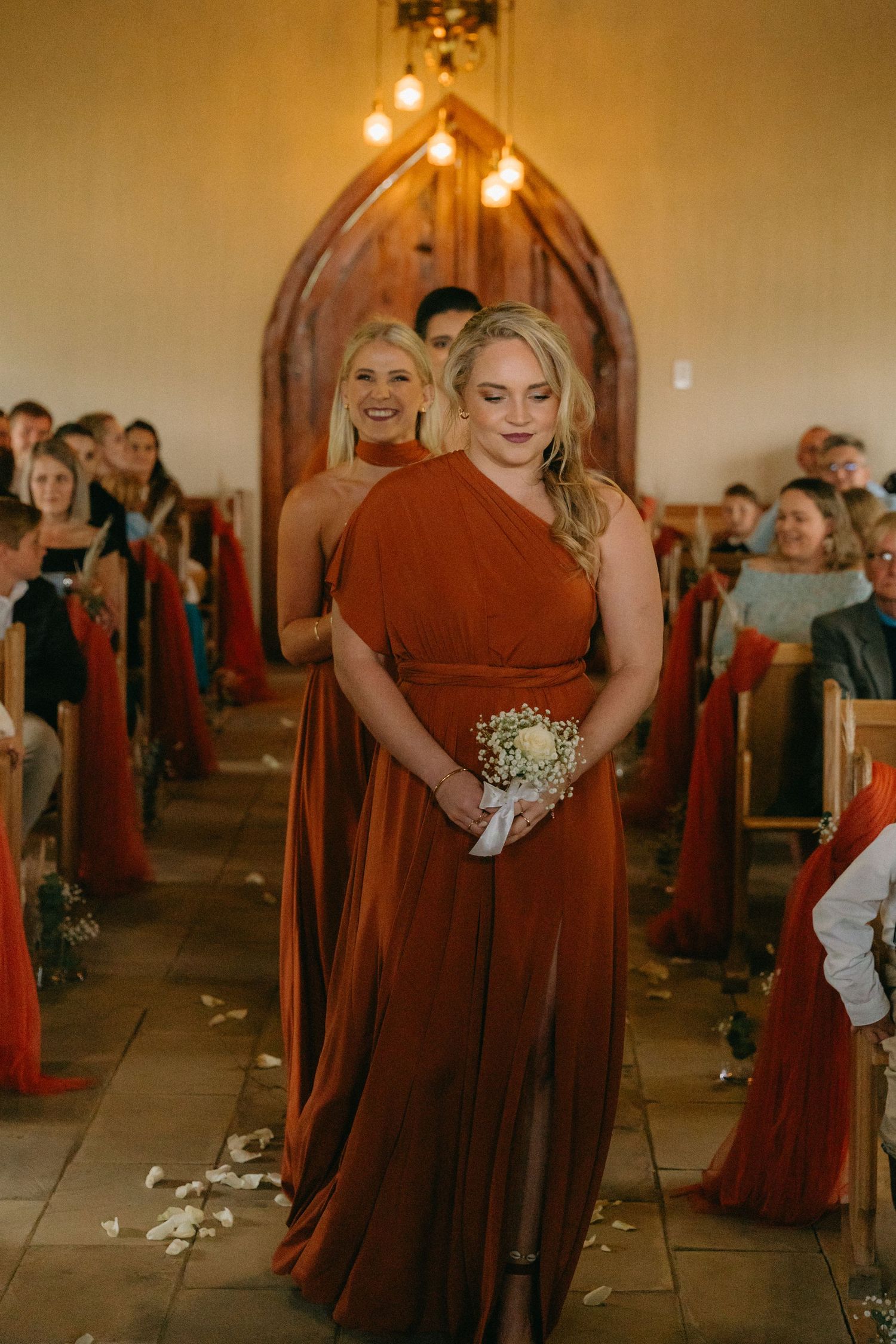 Wedding processional in a church with burgundy bridesmaid dresses and floral bouquets.