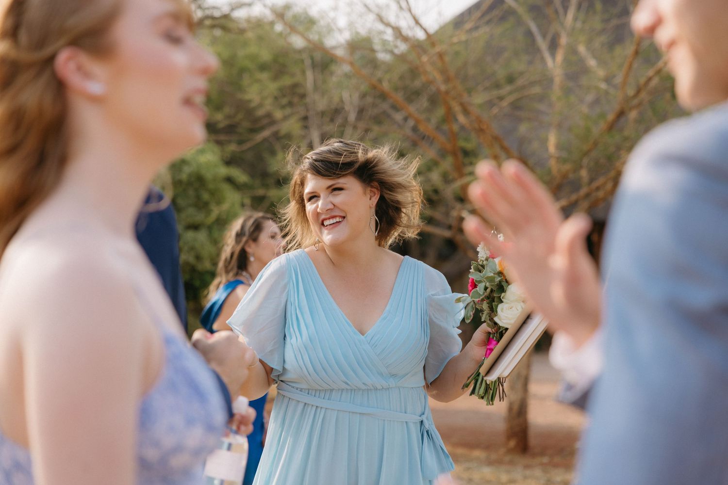 Wedding party members in light blue dresses and formal attire gathered outdoors.
