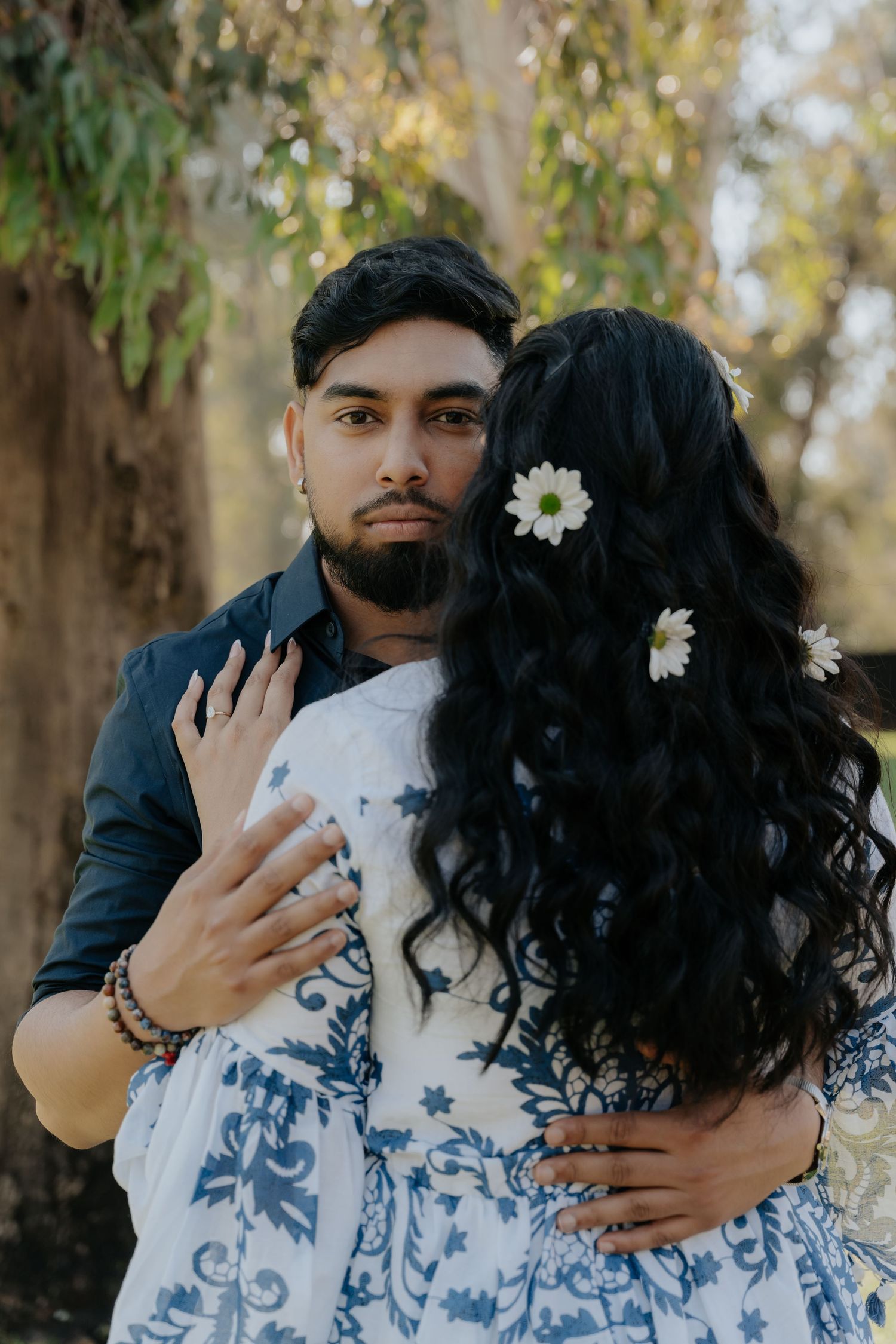 A tender moment captured between a couple in matching blue and white attire against a natural backdrop.
