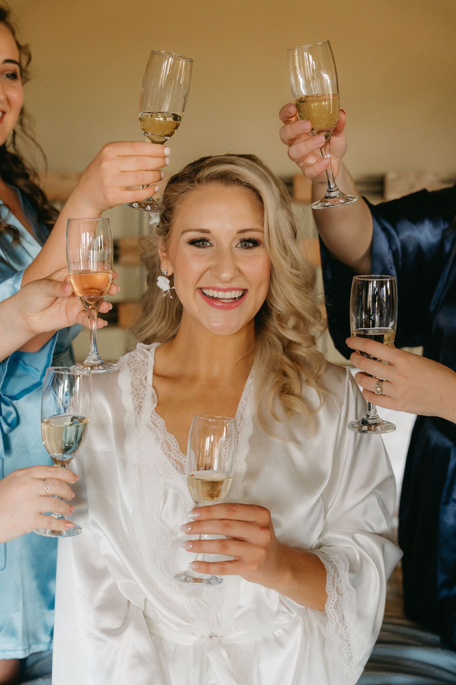Wedding party toasts with champagne glasses during pre-ceremony preparations.
