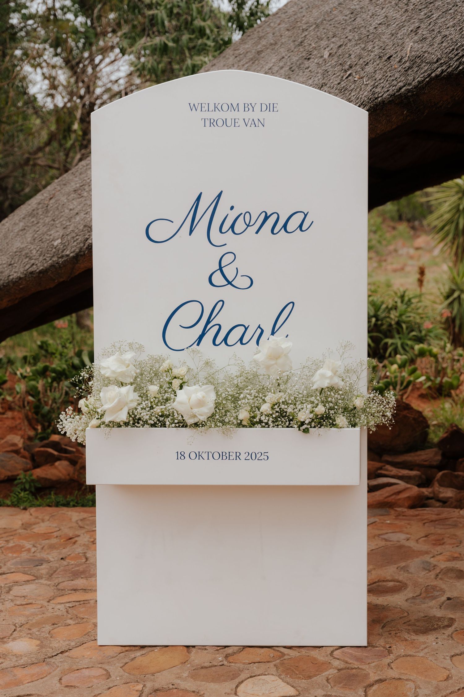 Elegant white wedding welcome sign with blue script text and baby's breath flowers.