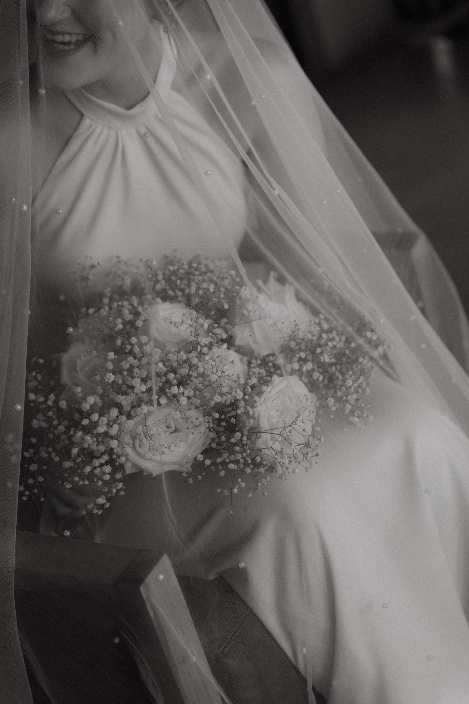 Bride holds bouquet of roses and baby's breath beneath flowing wedding veil at Mountain View Game Lodge
